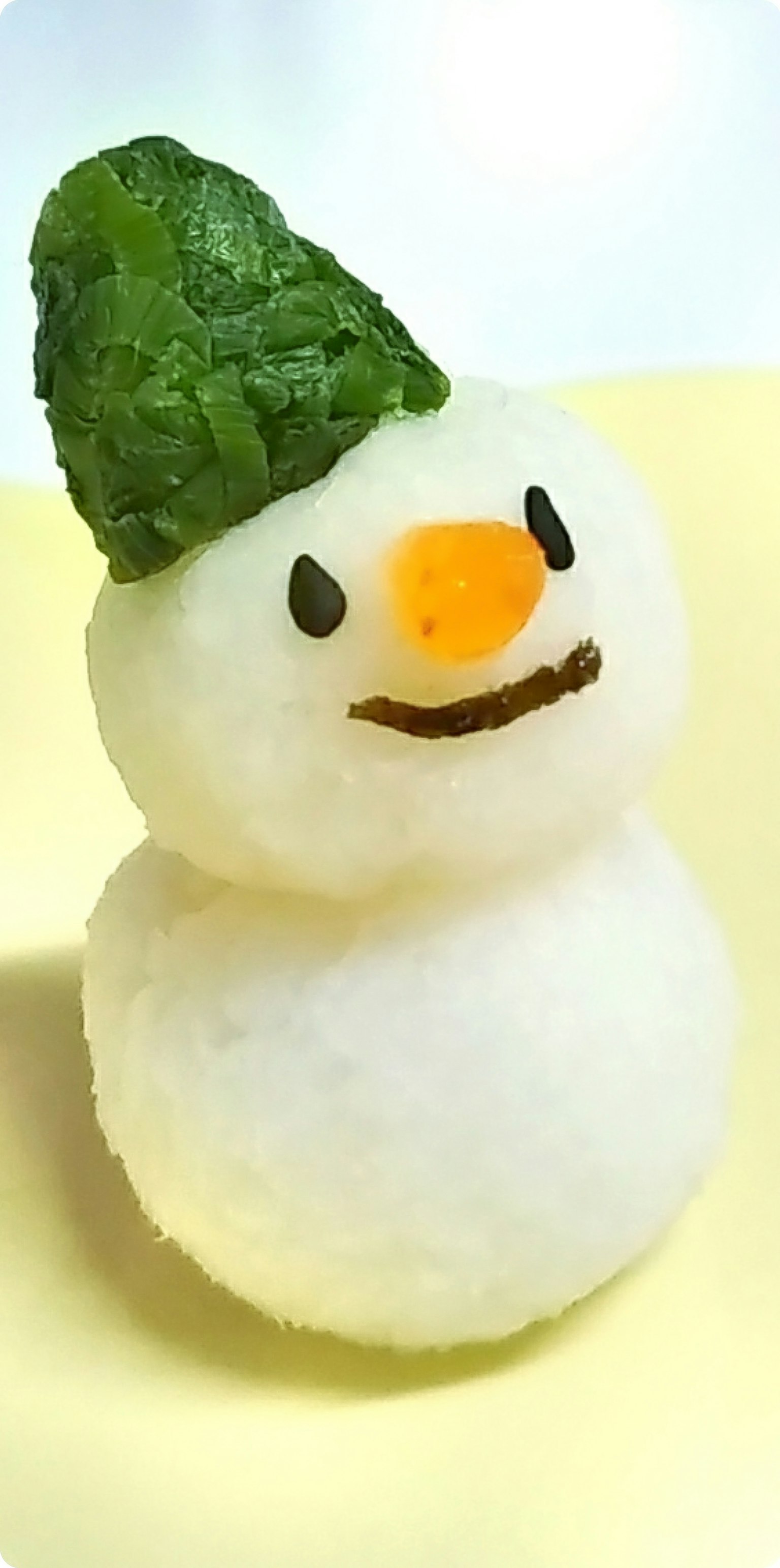 Un piccolo cibo a forma di pupazzo di neve con un cappello verde e un naso arancione