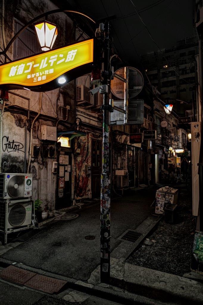 看板と自販機が並ぶ薄暗い路地の夜景