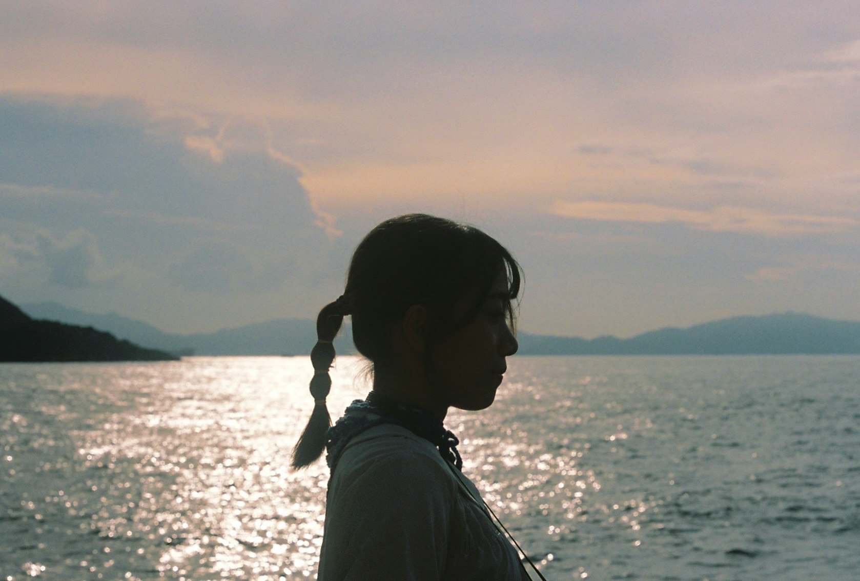 夕暮れの海を背にした横顔の女性