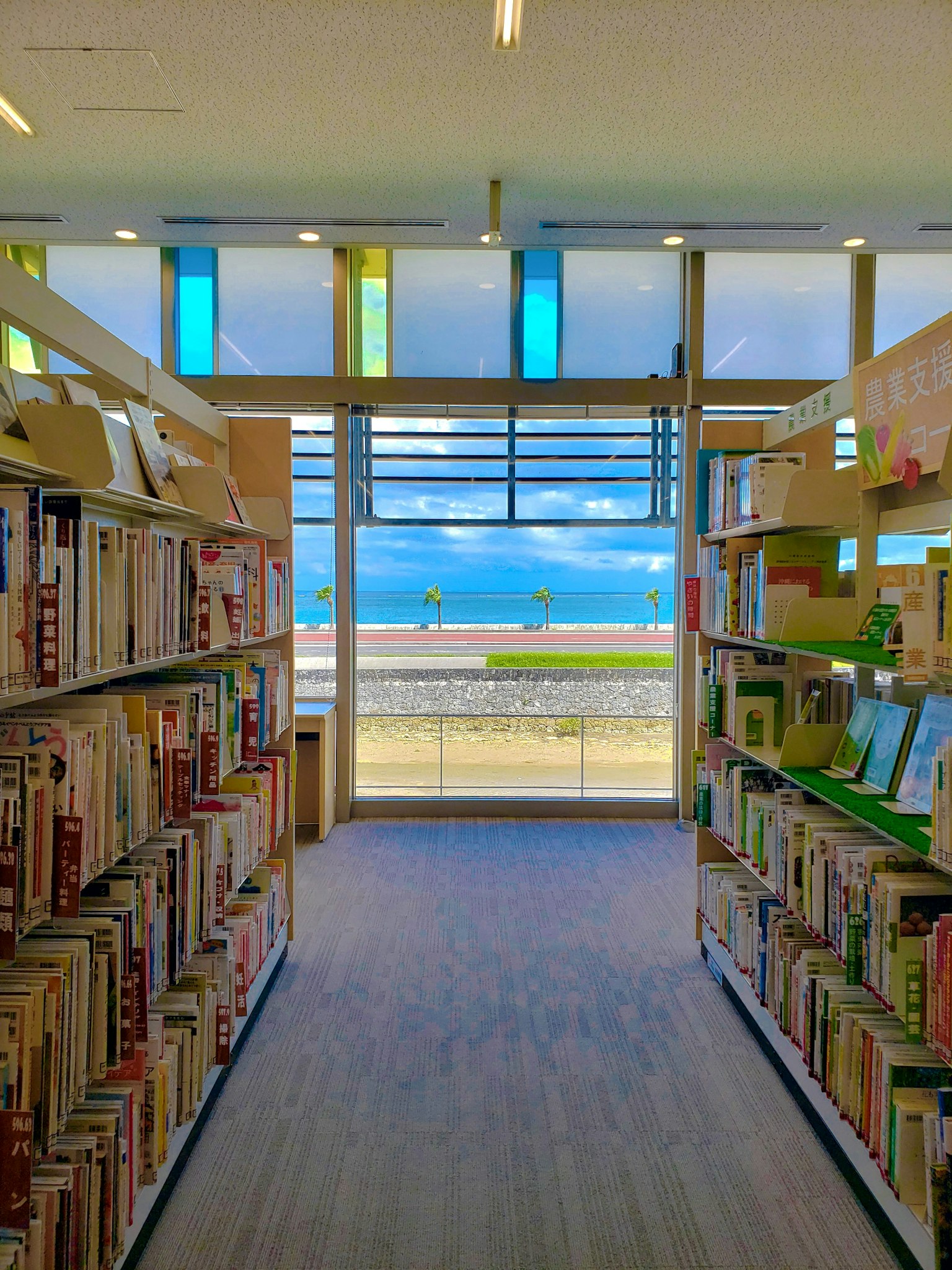 Intérieur d'une bibliothèque avec des étagères et une vue sur la mer à travers des fenêtres colorées