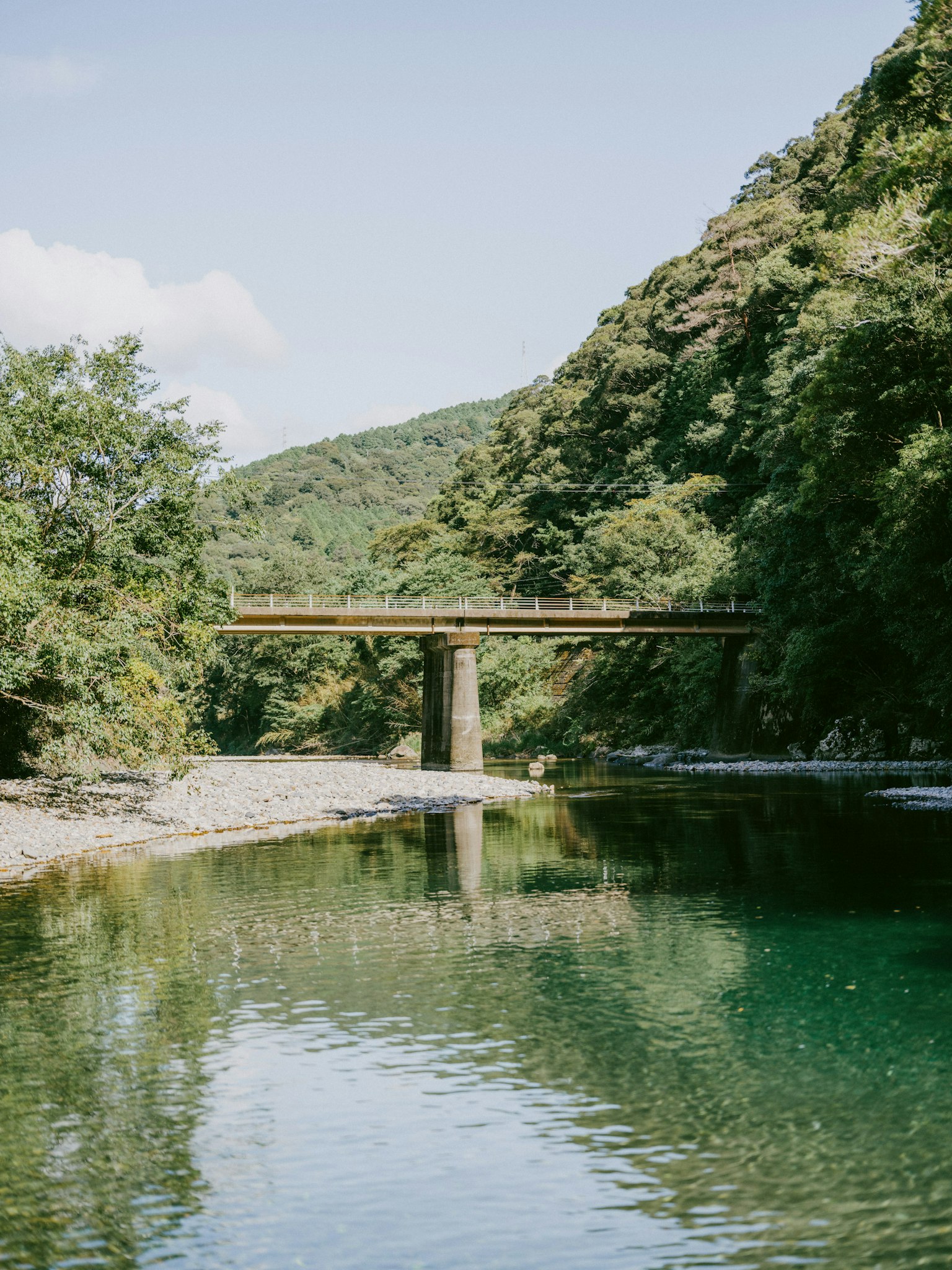 Paisaje de río escénico con un puente de madera rodeado de montañas verdes
