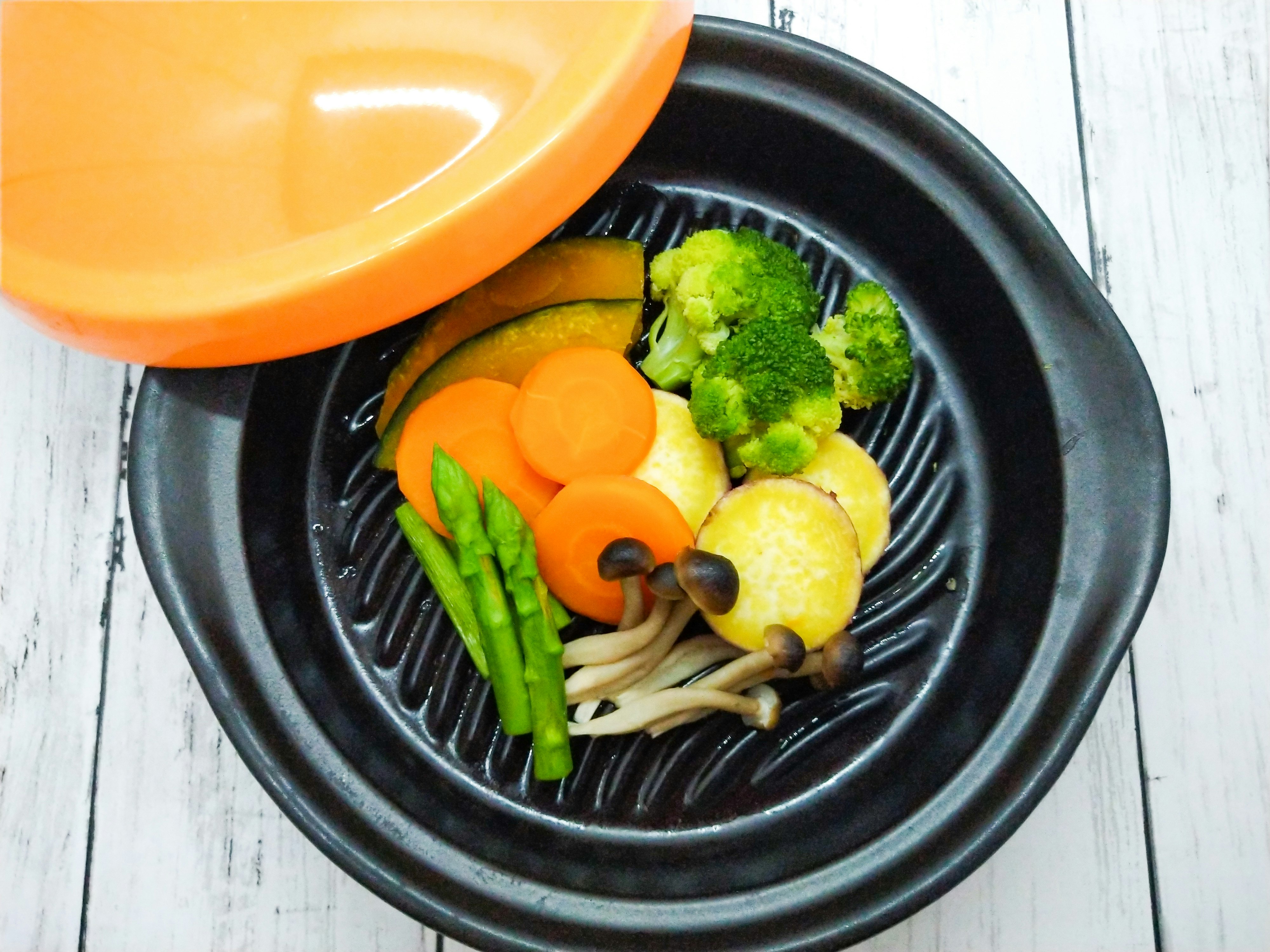 Mélange de légumes en cuisson dans une marmite avec un couvercle orange