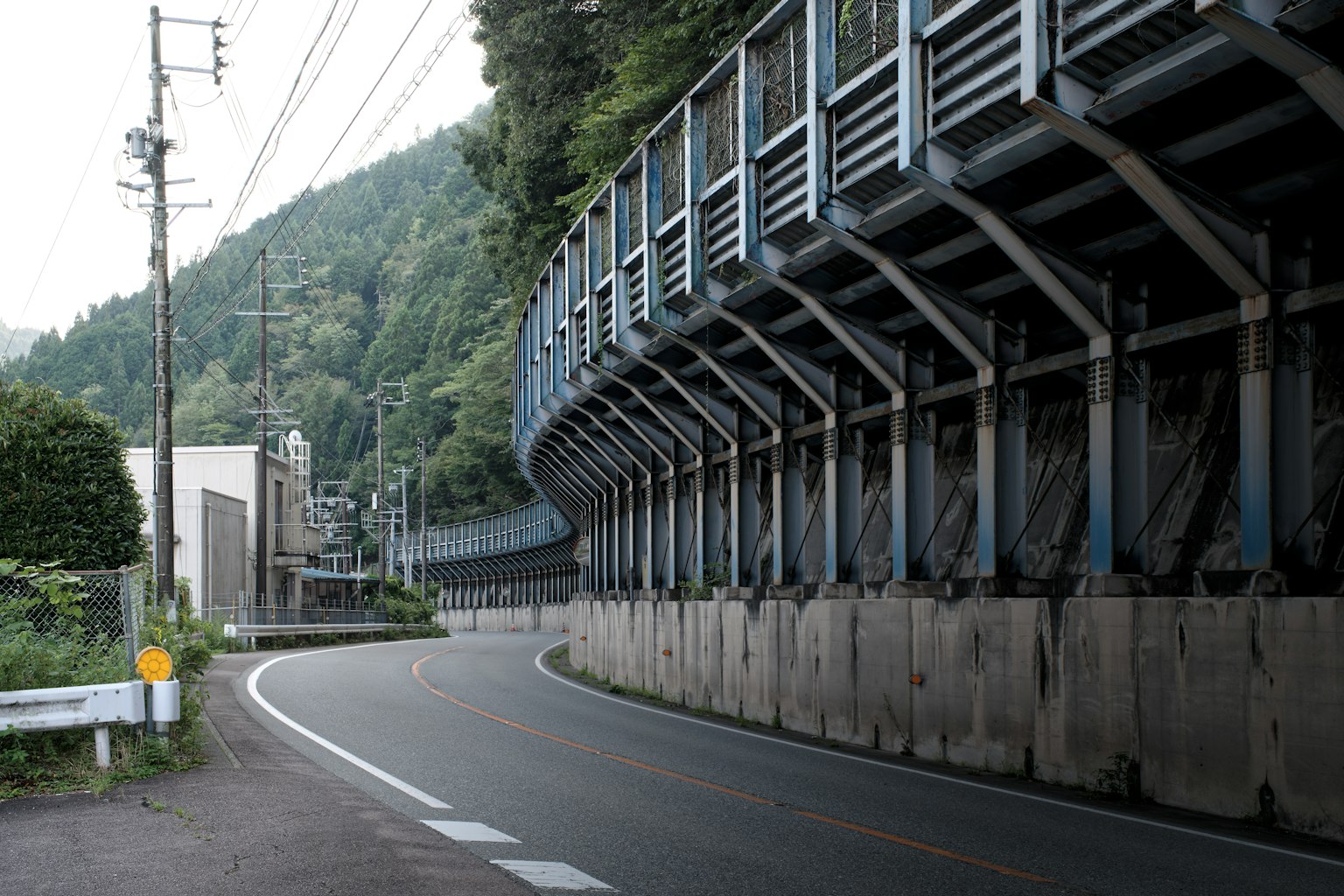 Strada curvilinea circondata da montagne con una barriera di sicurezza in metallo