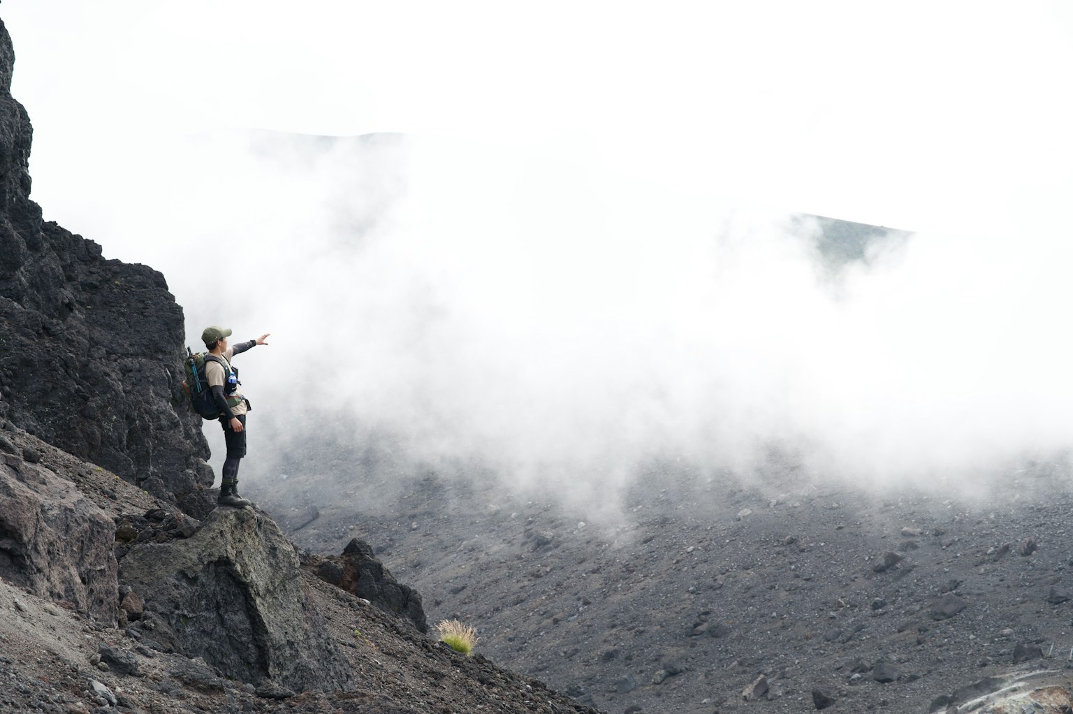 一个人站在火山口指向烟雾