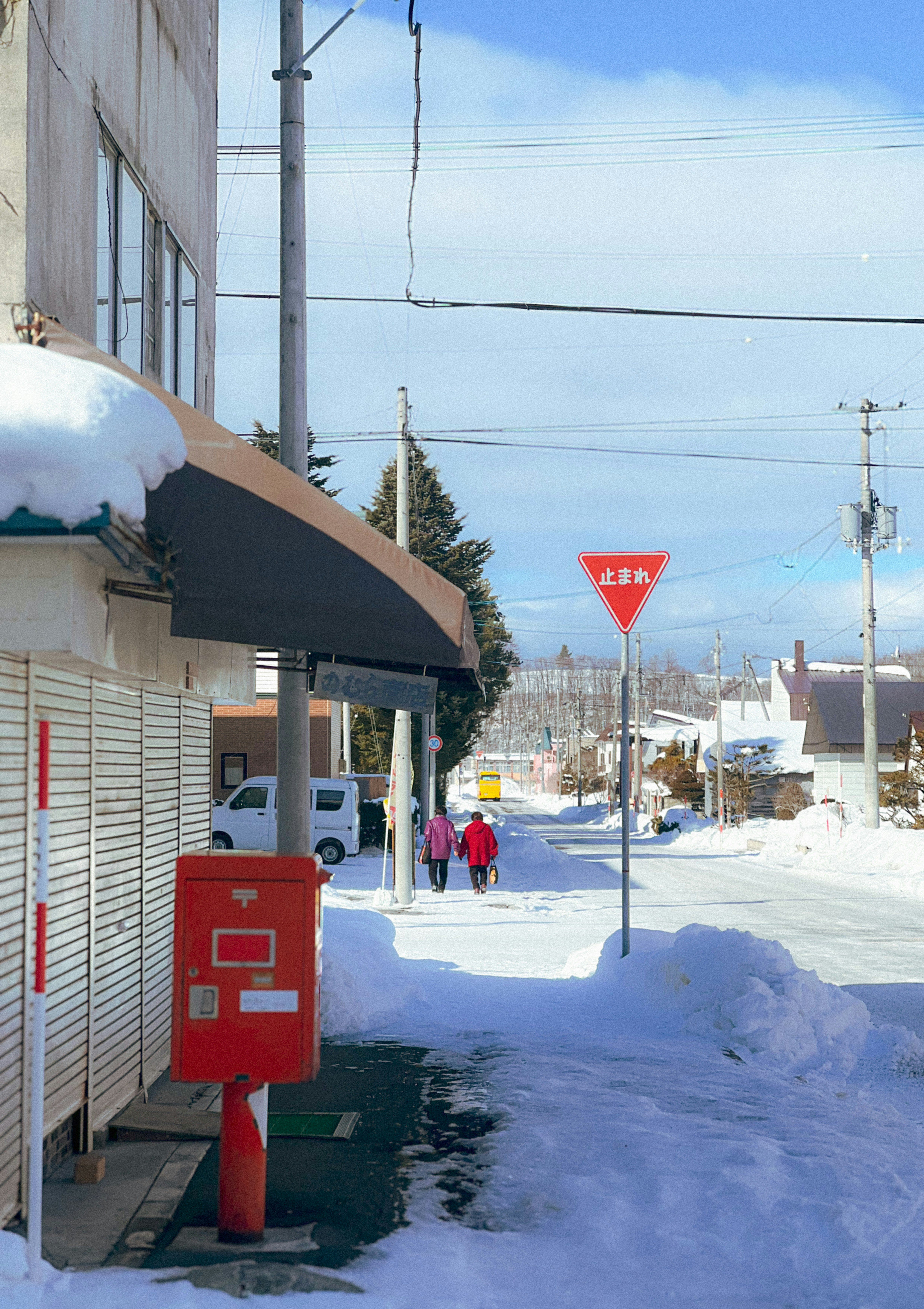 積雪的人行道街道，建築與紅色信箱