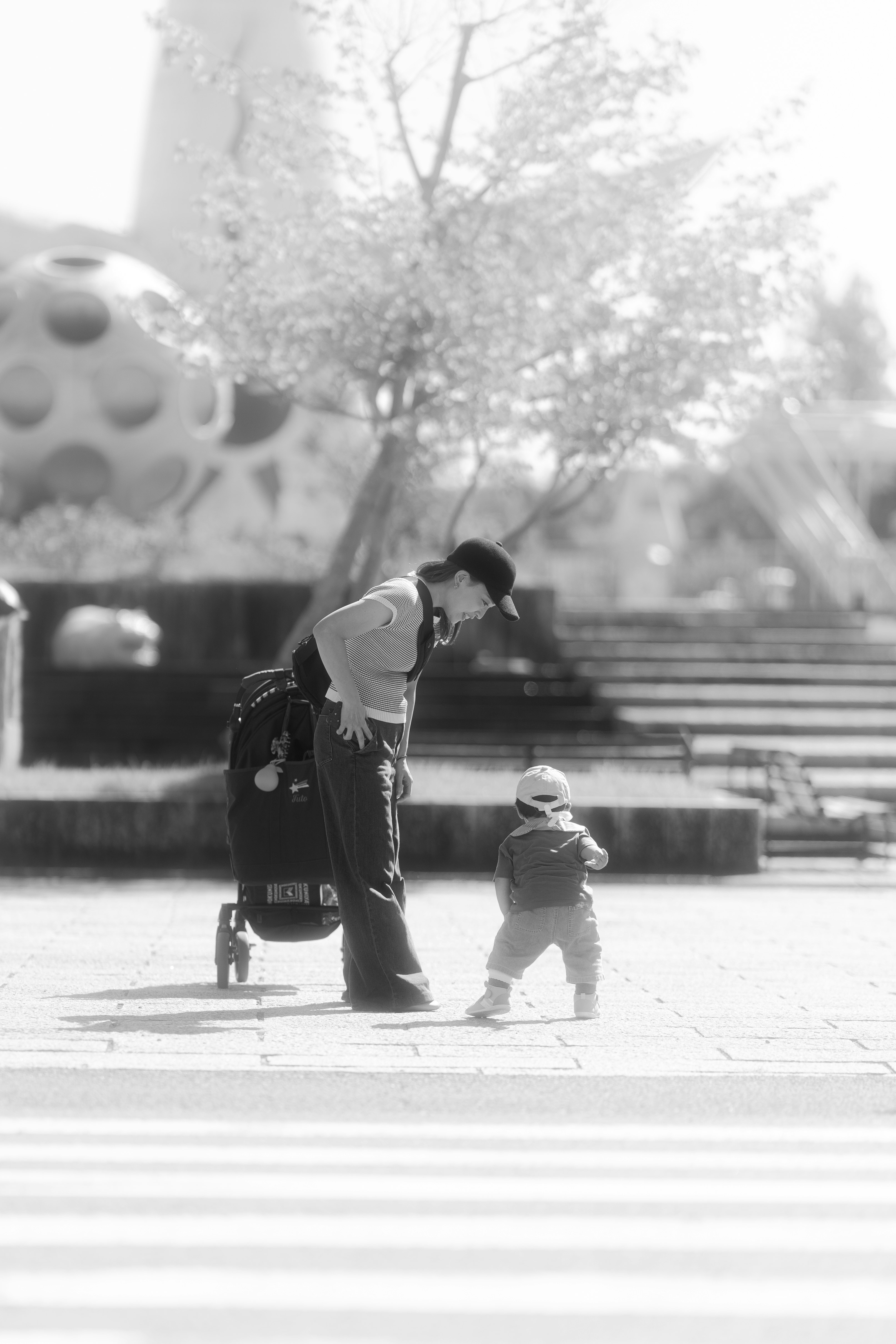 モノクロの公園でベビーカーを押す親子の何気ない瞬間