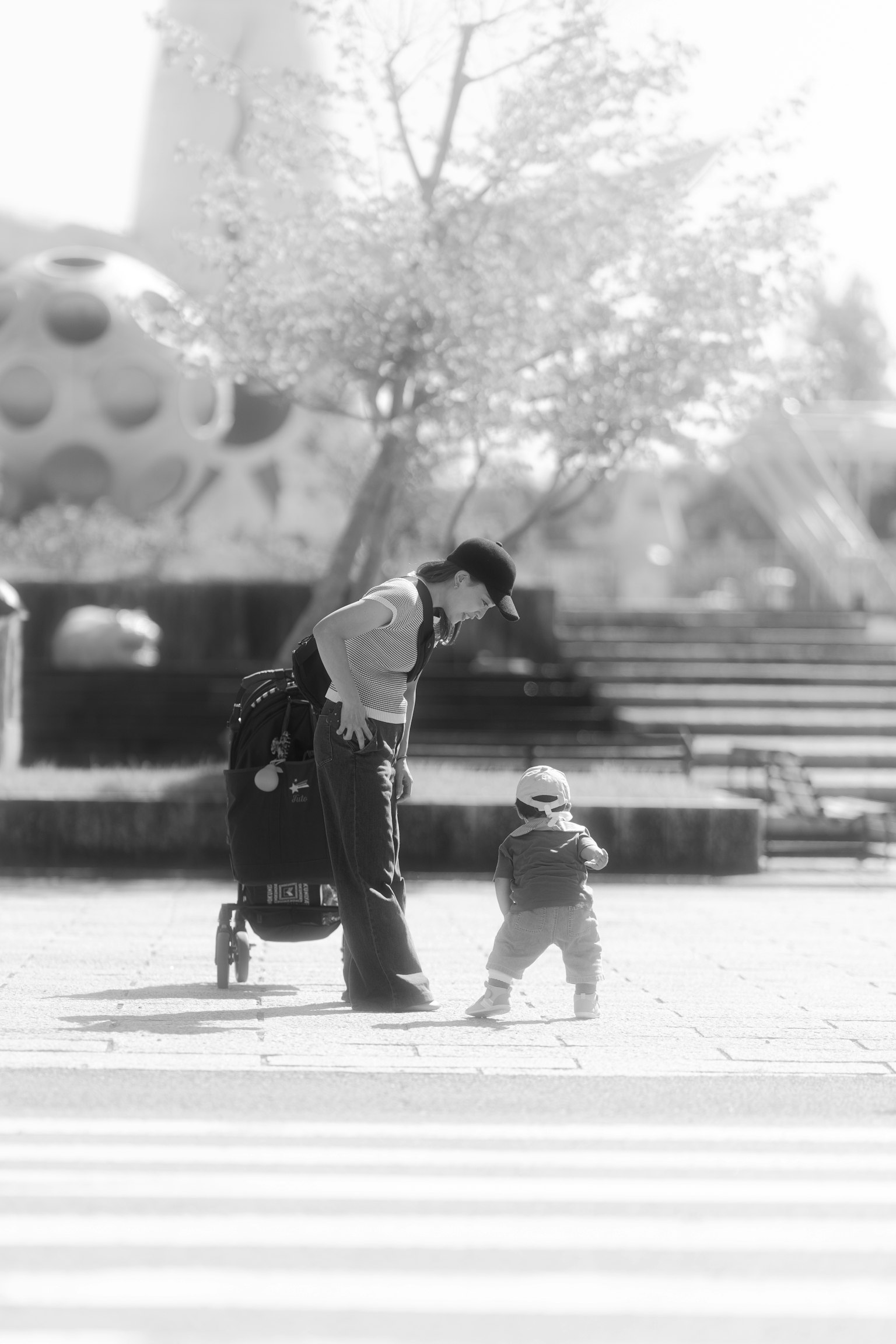 親子が歩道を渡るシーン　父親が子供を見守る　背景に遊具のある公園