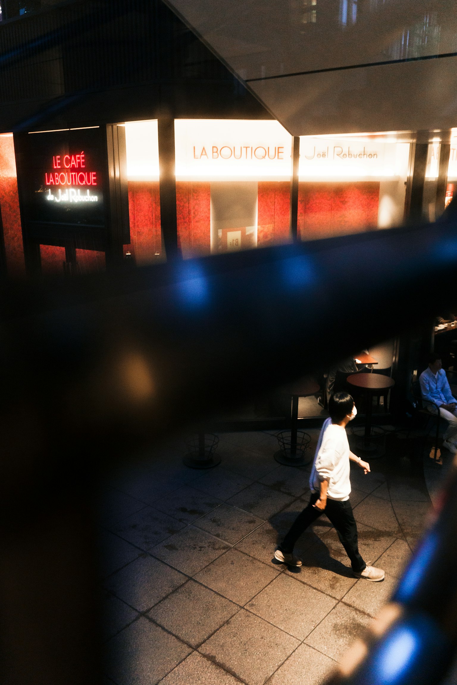 一個人在夜間街道上走，旁邊有霓虹燈