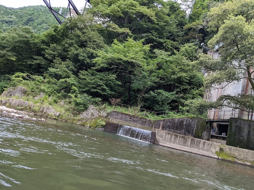 緑の森に囲まれた小さな堰と流れる川の風景
