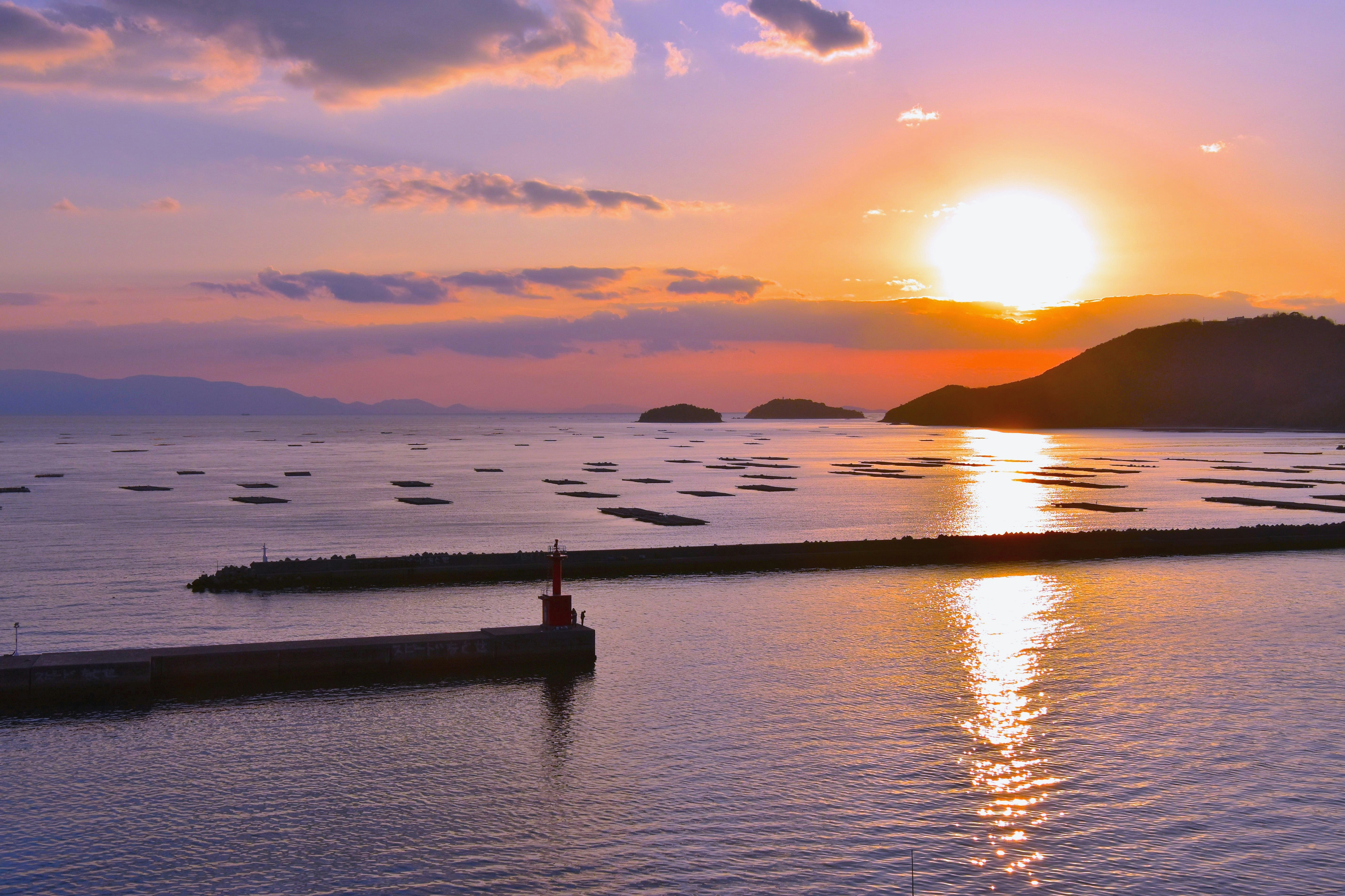 夕日に照らされる海と防波堤のある港の風景