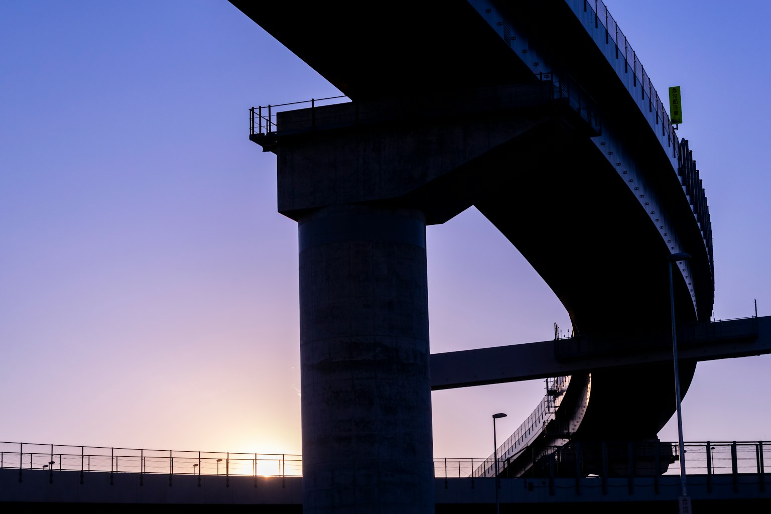 Silueta de un puente y una vía elevada contra un hermoso atardecer