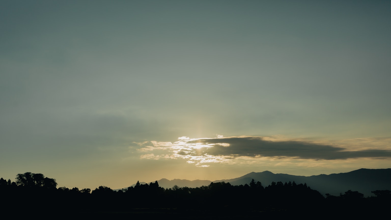 Silhouette of mountains and clouds against a blue sky