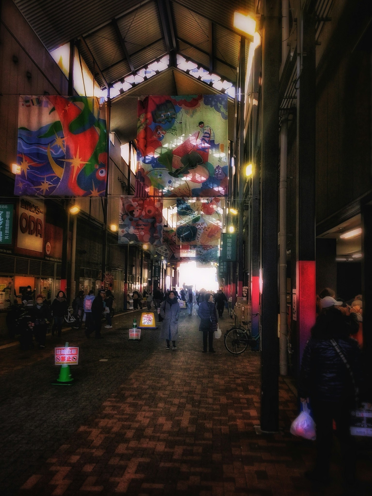 Interno di una vivace strada di mercato con striscioni colorati appesi e varie persone che passeggiano
