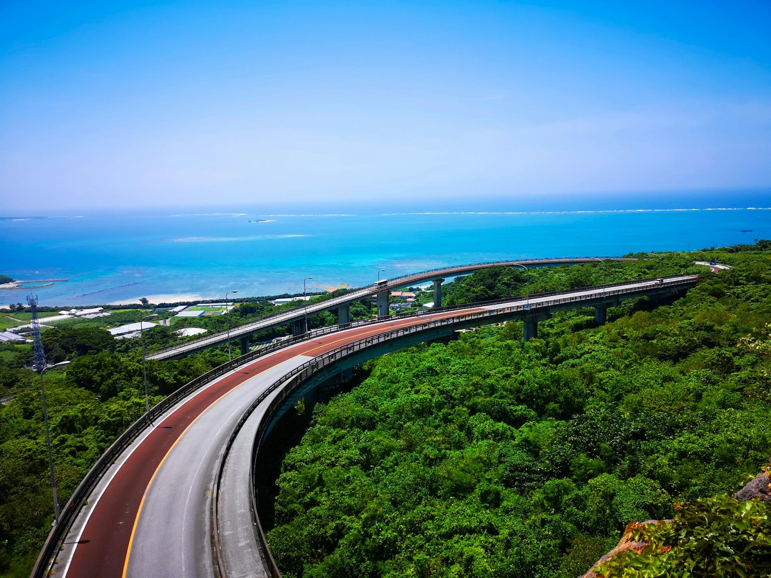 被绿色山丘和蓝色海洋环绕的弯曲道路