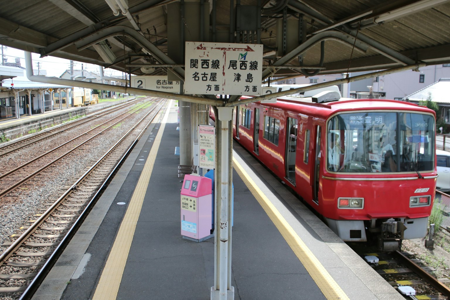 Kereta merah di platform stasiun dengan papan petunjuk