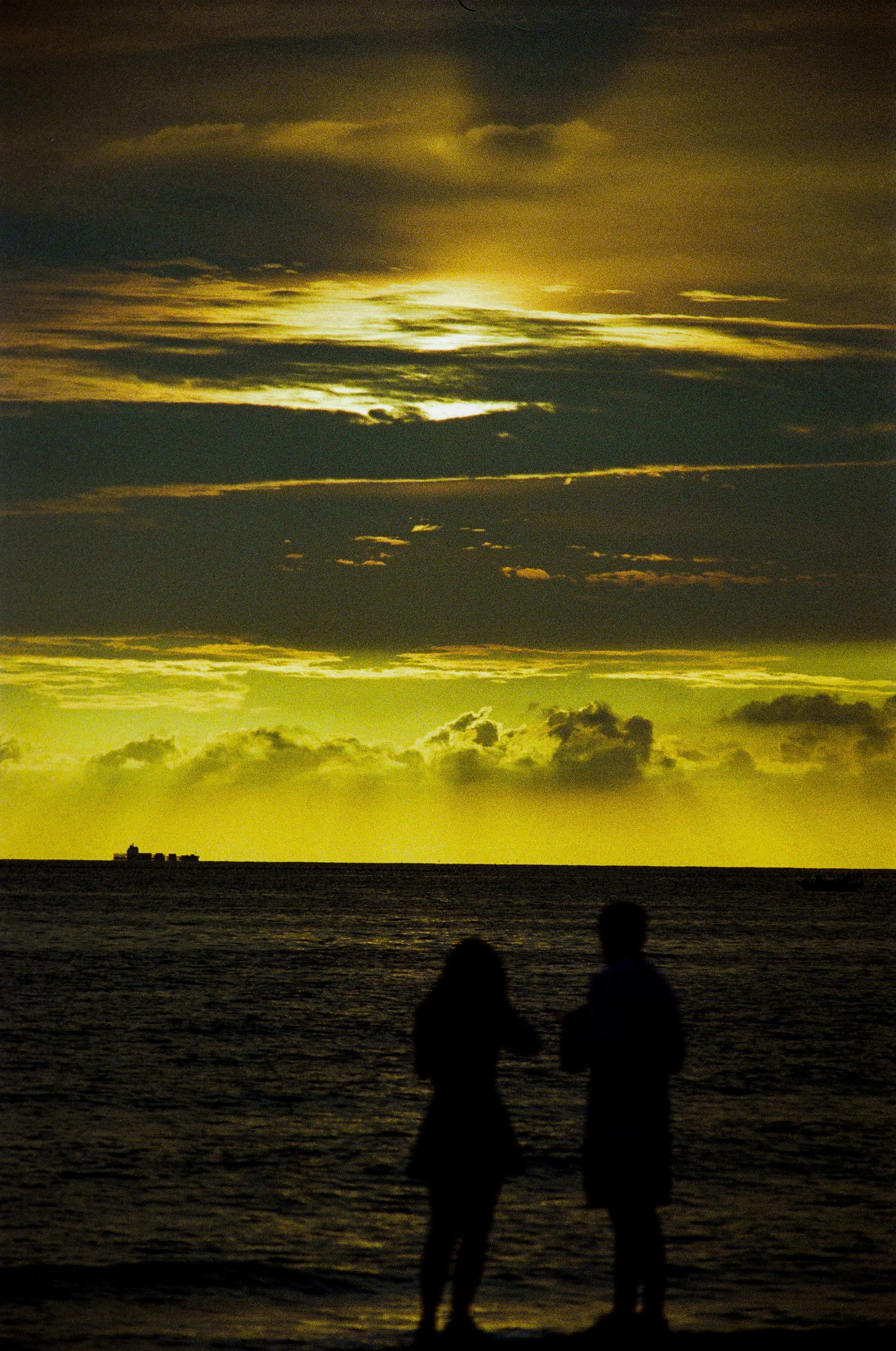 夕陽の海辺で寄り添う恋人たちのシルエット