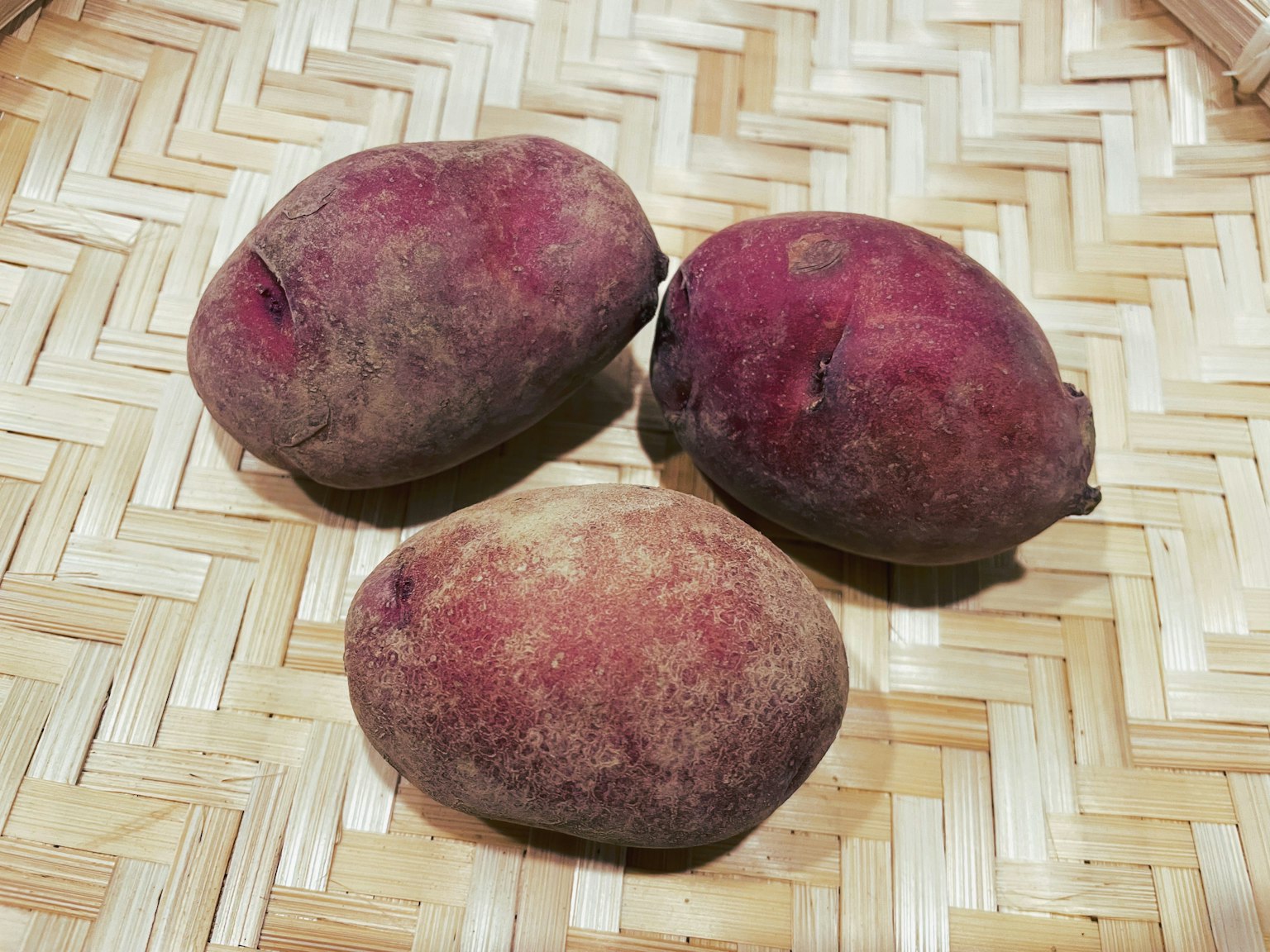 Tres batatas moradas colocadas sobre una canasta tejida
