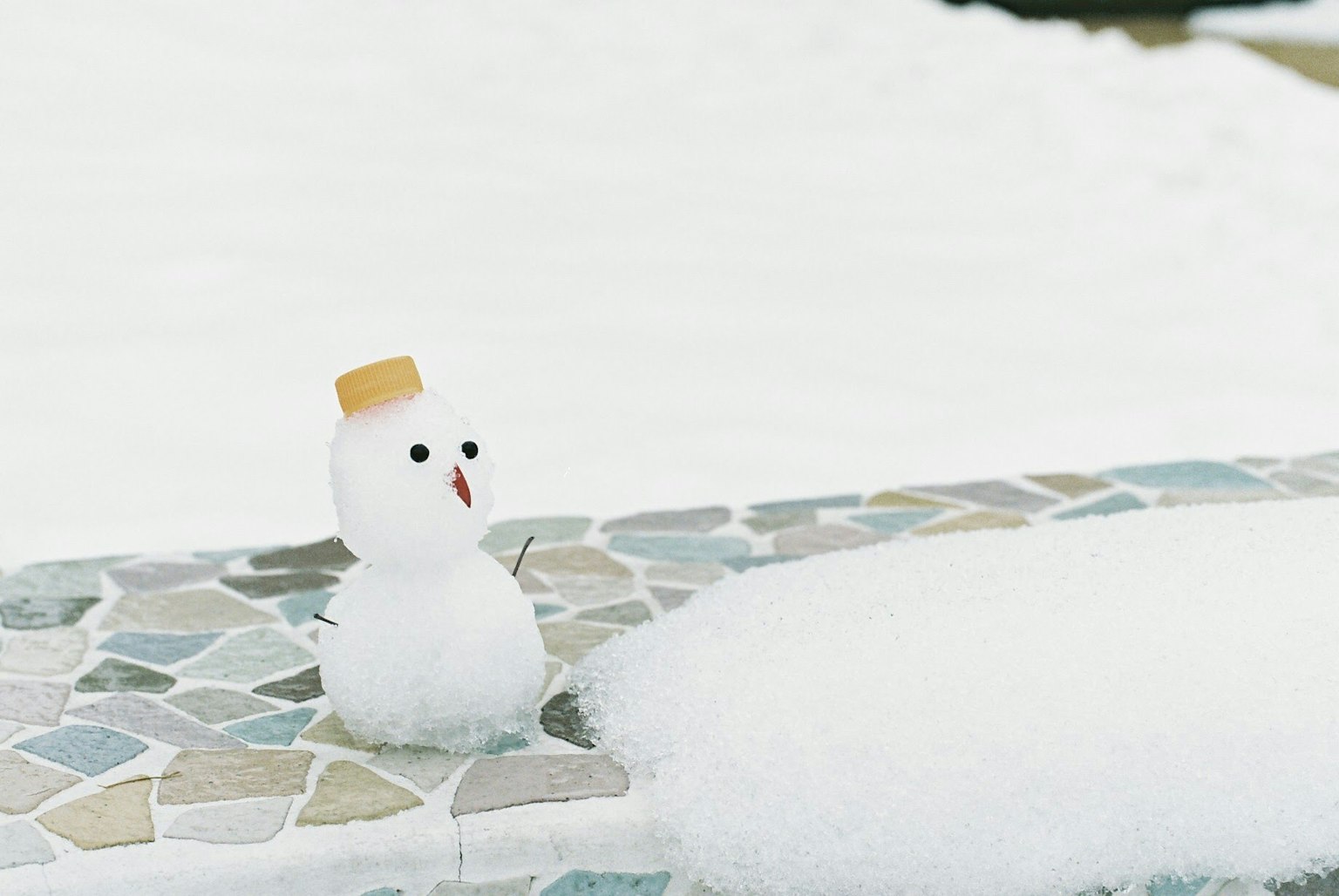 Snowman with a yellow hat on a snowy surface