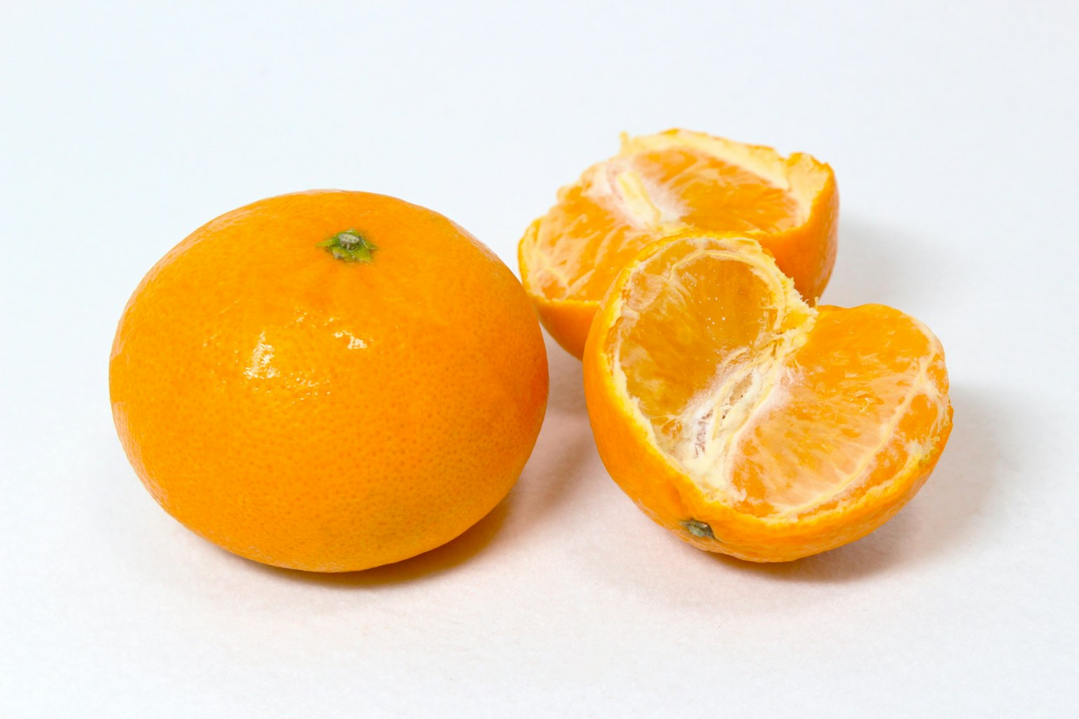 Eine ganze Orange und ihre halbierten Segmente auf einem weißen Hintergrund