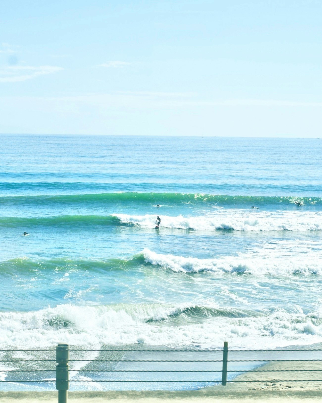 海辺の波打ち際を歩く人々のある海景