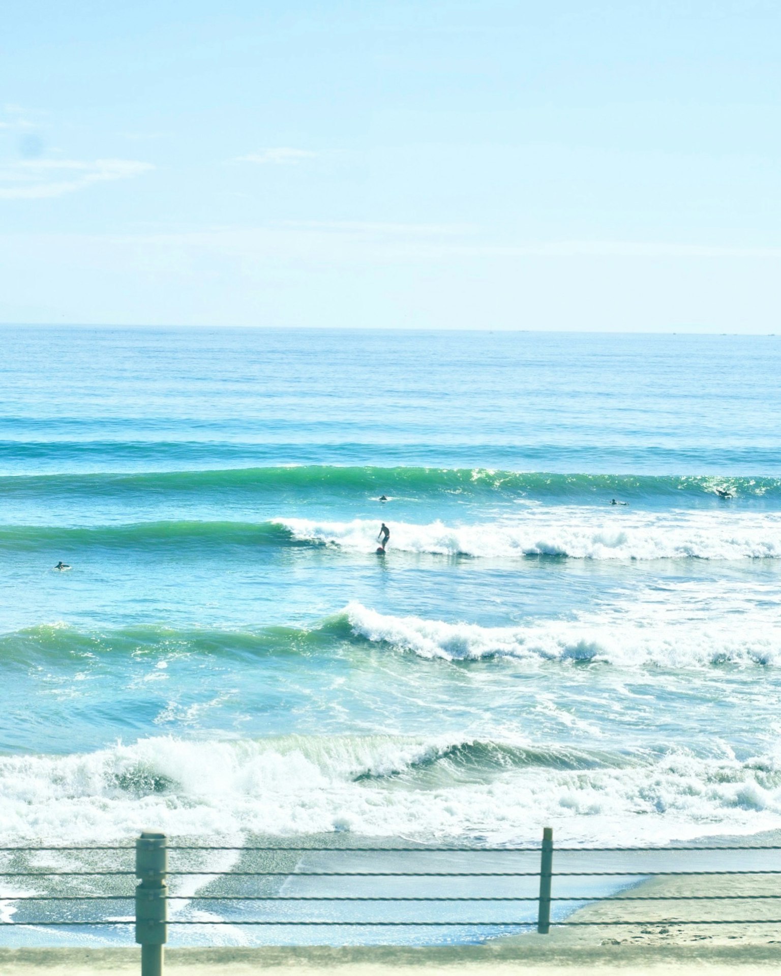 Surfista montando olas en un océano azul bajo un cielo despejado