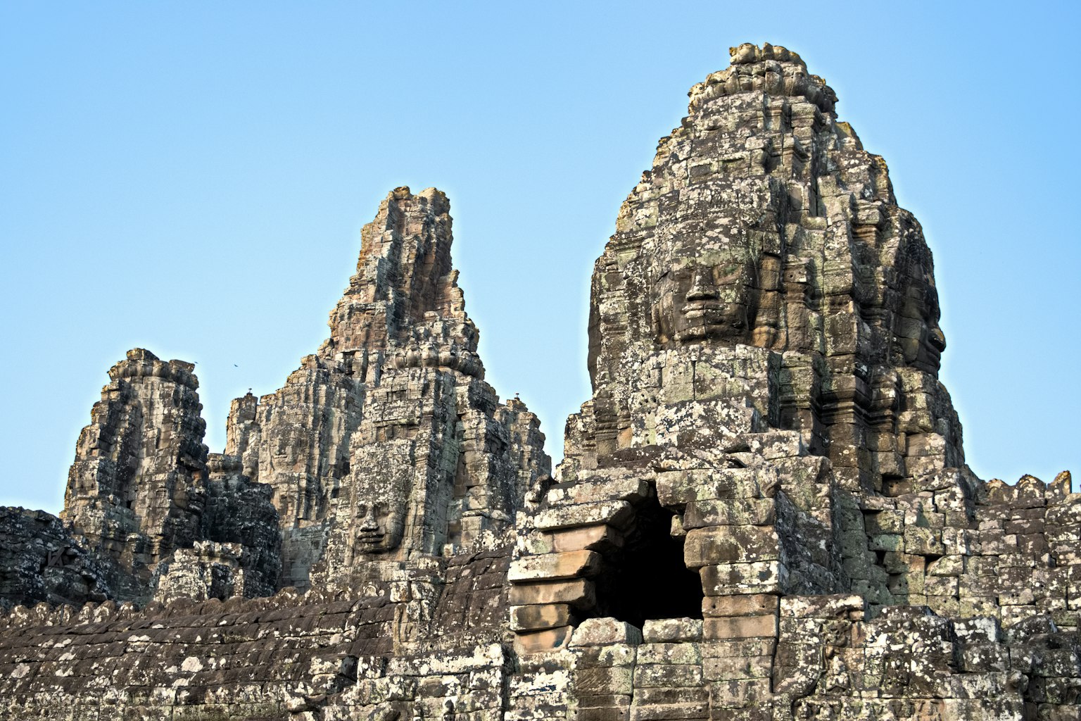Rovine di un antico tempio in pietra con strutture torreggianti e volti scolpiti