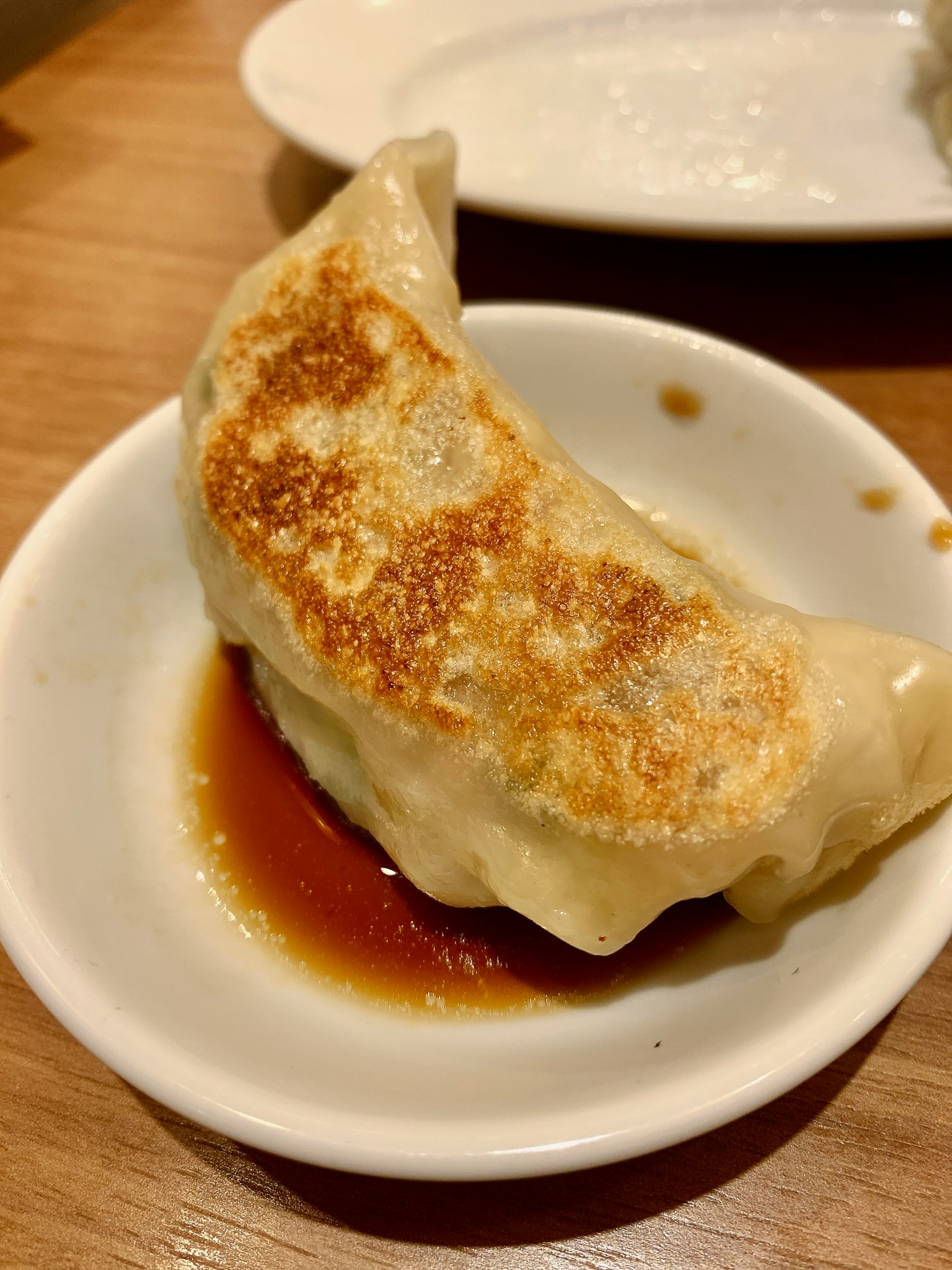 Gyoza fritos servidos en un plato pequeño con salsa de soja
