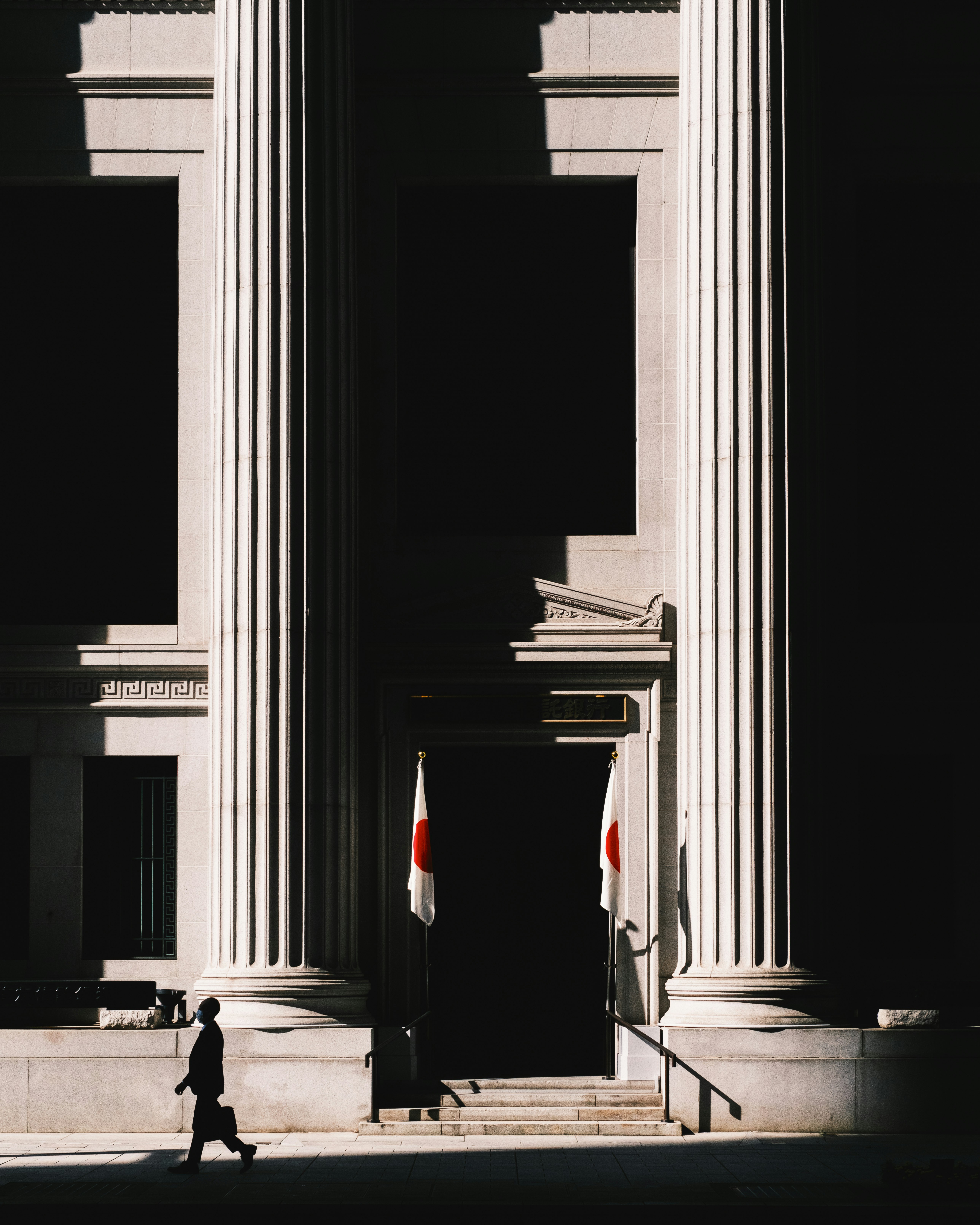 Exterior of a grand building with tall columns and a person walking
