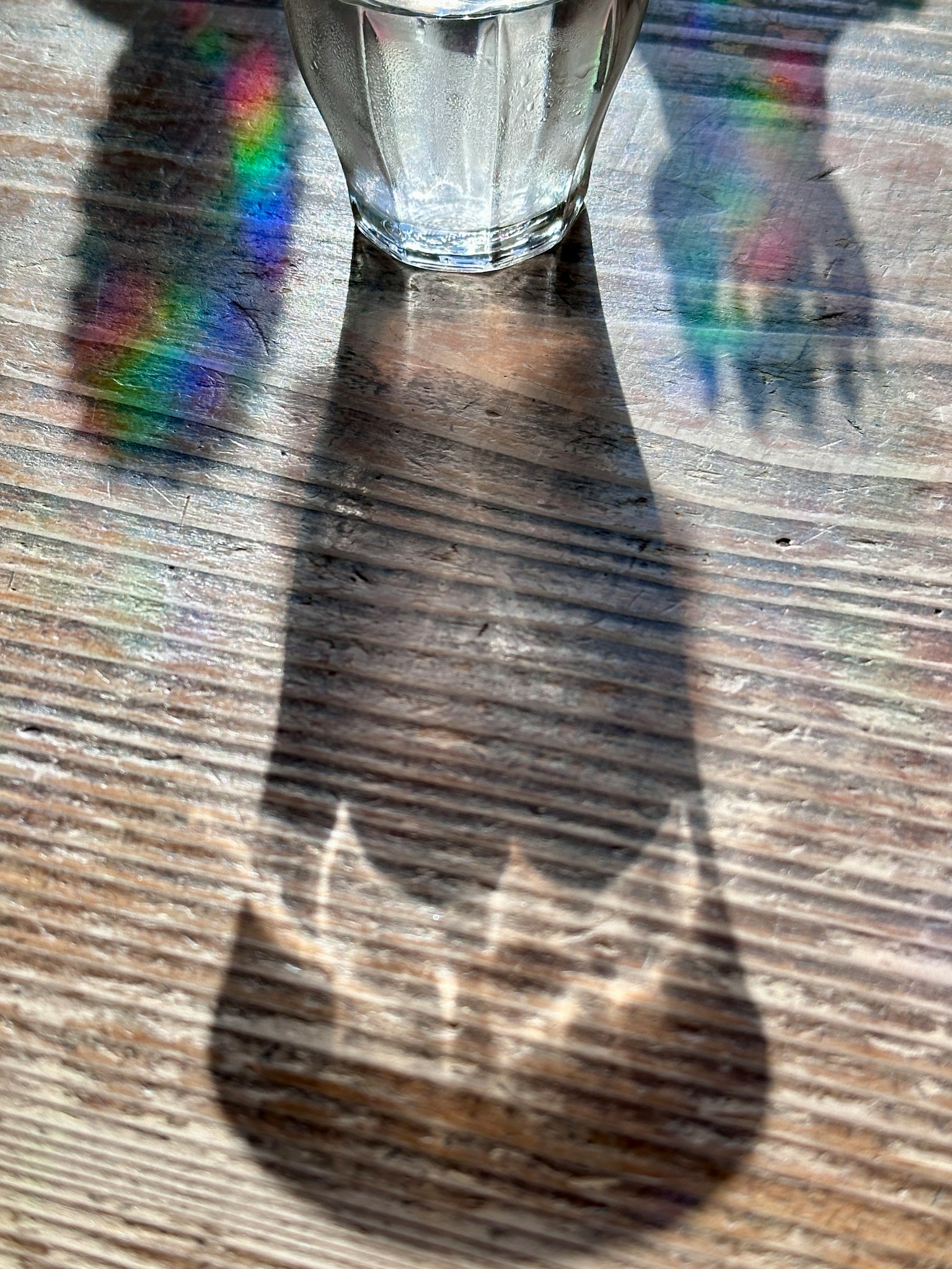 เงาสีรุ้งและรูปมือที่ถูกฉายโดยแก้ว