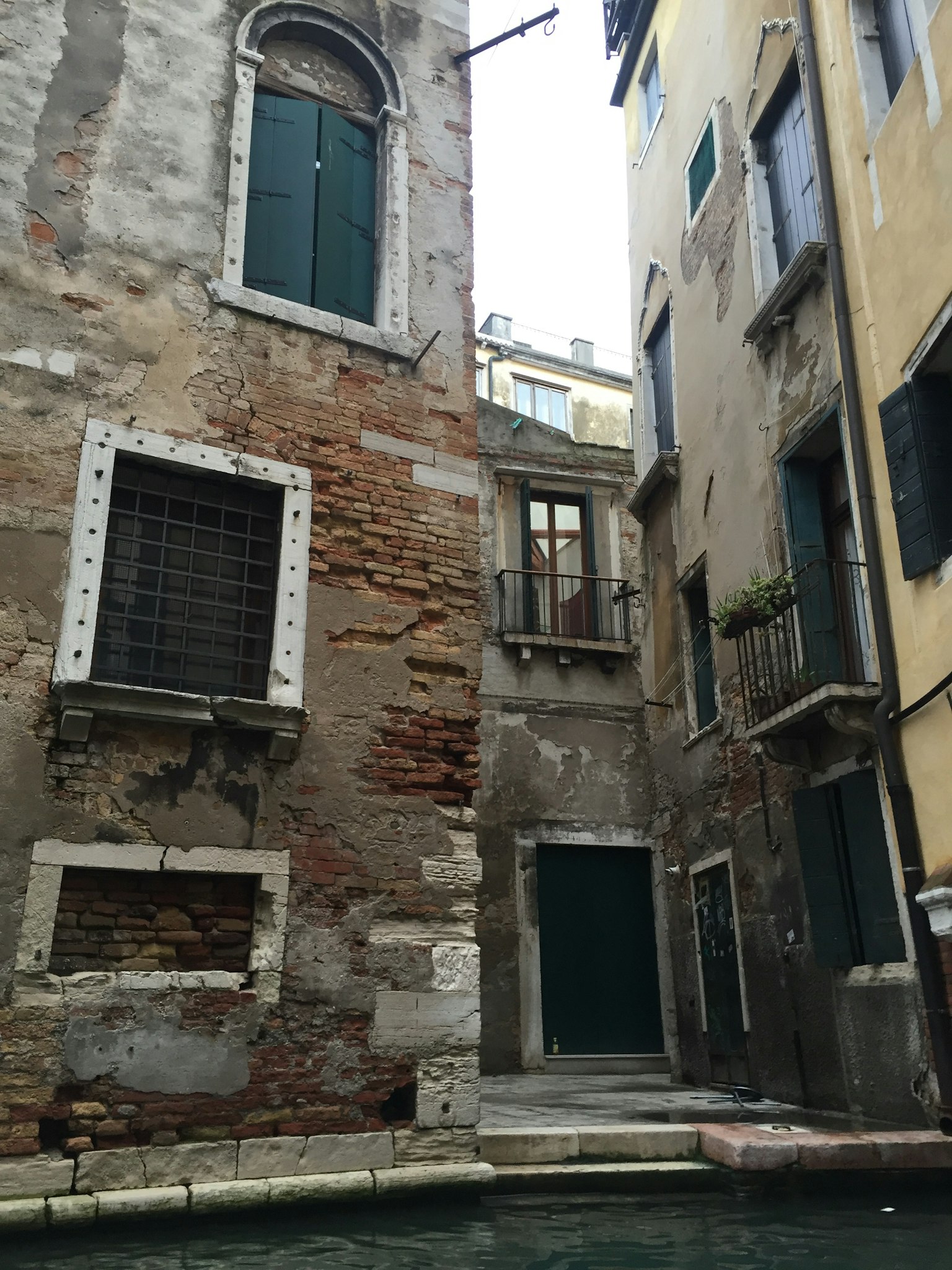 Old building walls along a canal with green doors
