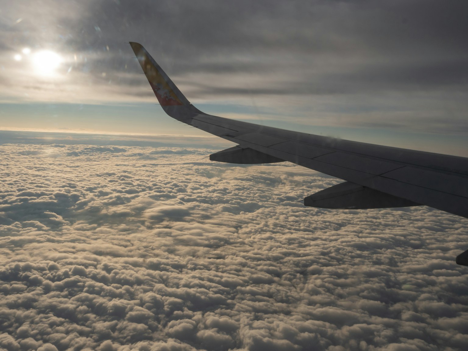Airplane wing above a sea of clouds with a dramatic sky