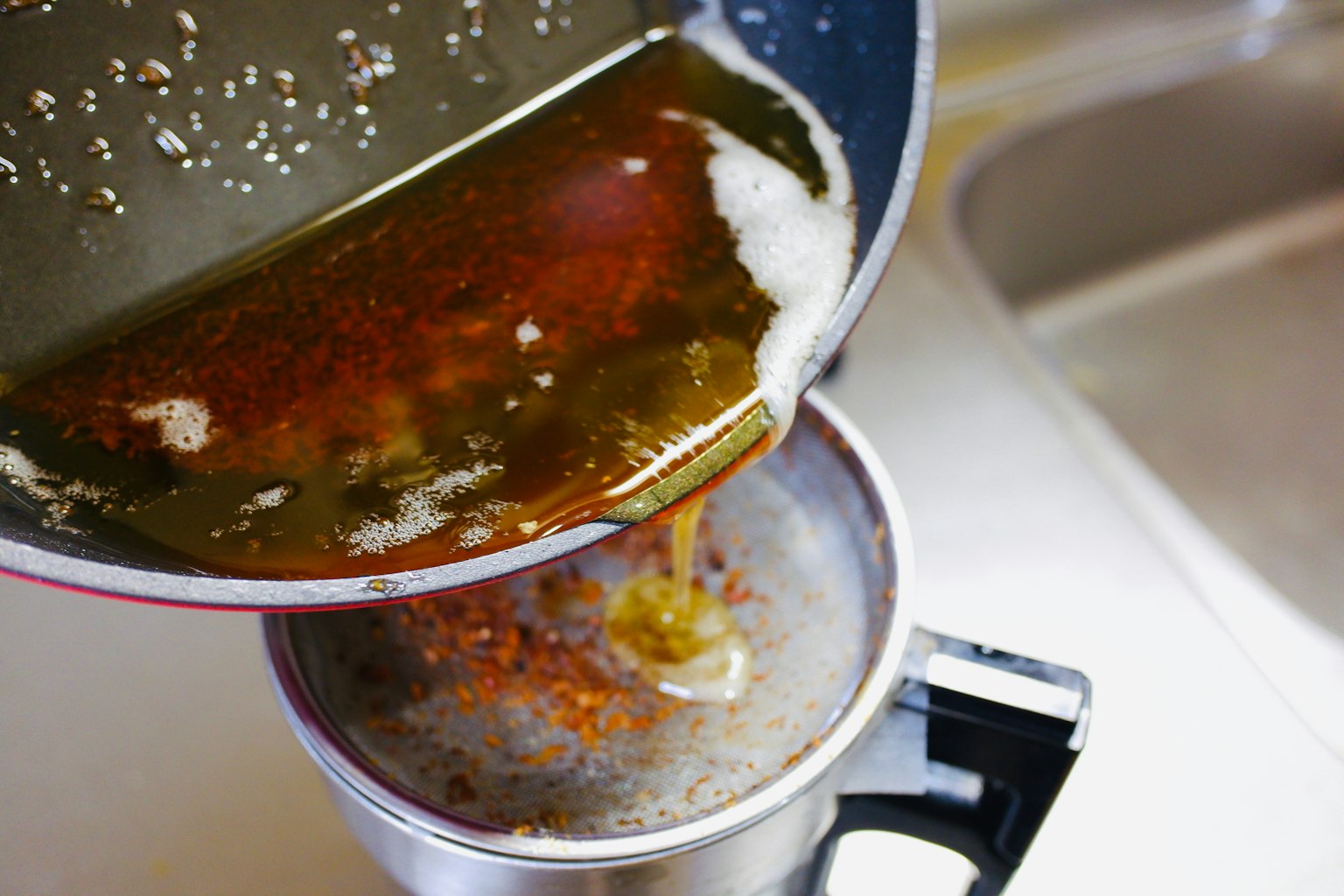 Versando olio in un colino in un contenitore
