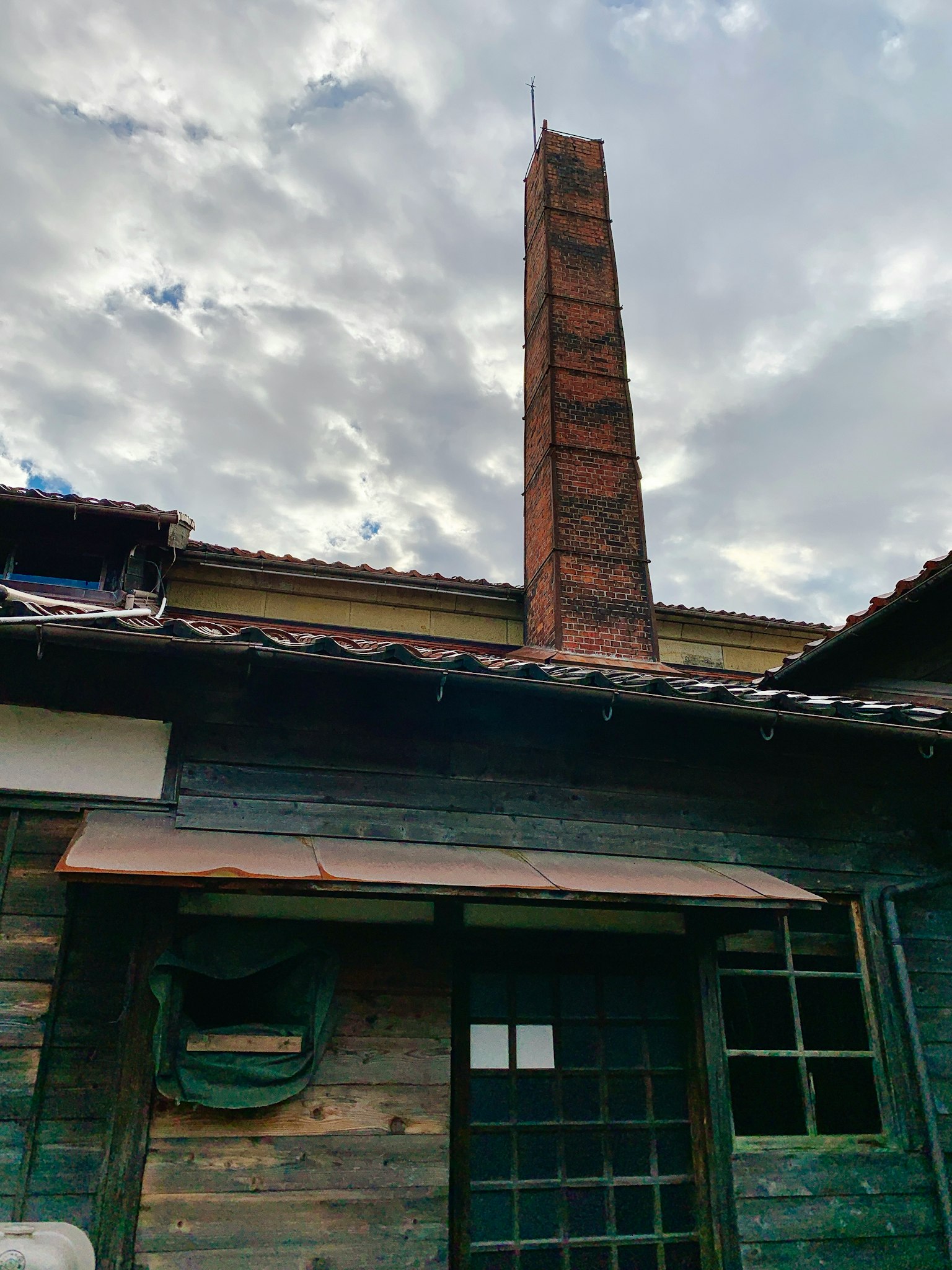古老的木造建築和高煙囪在多雲的天空下