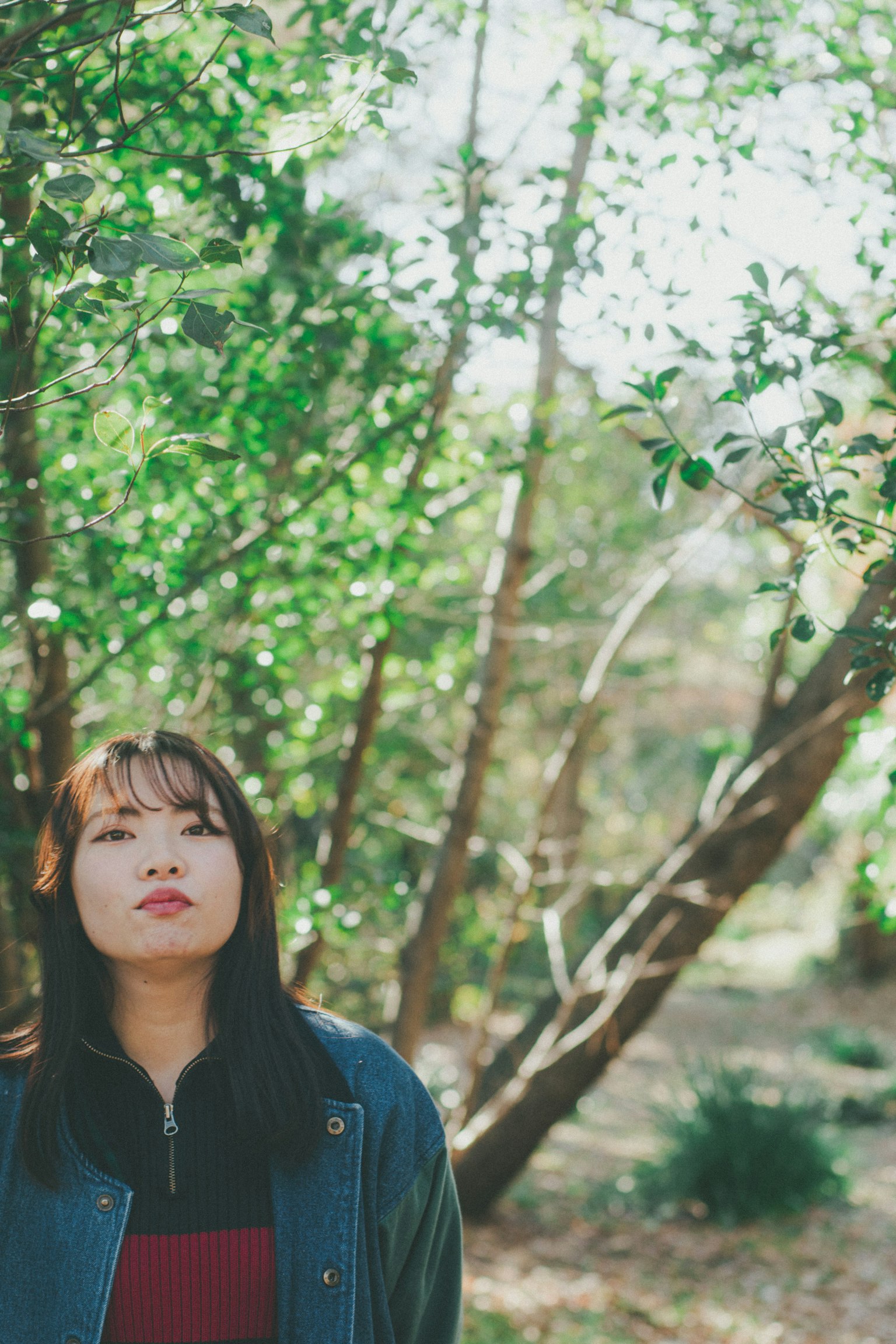 在綠色樹木中思考的女性肖像
