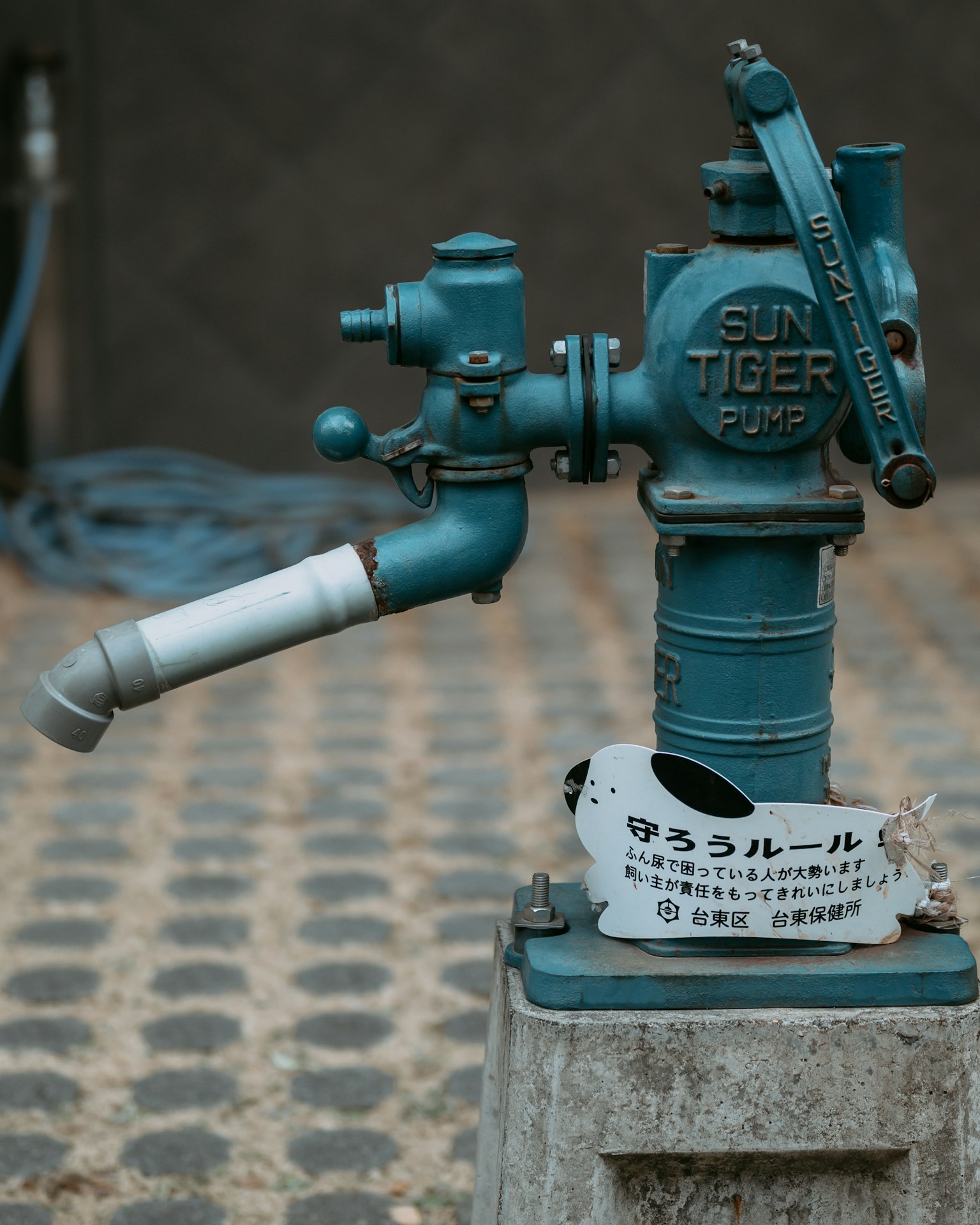 Blaue Wasserpumpe mit einzigartigem Design und Kopfsteinpflaster-Hintergrund