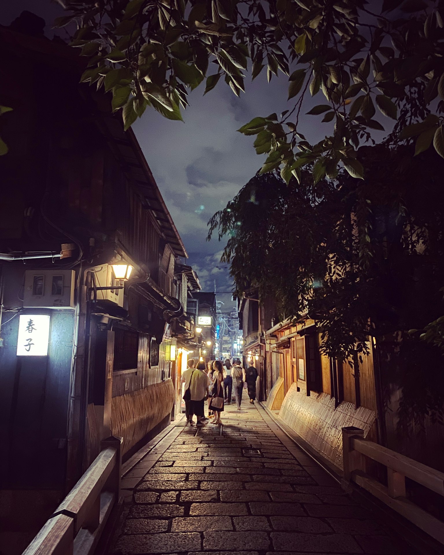 Cảnh đêm của một con phố lát đá ở Kyoto với người đi bộ