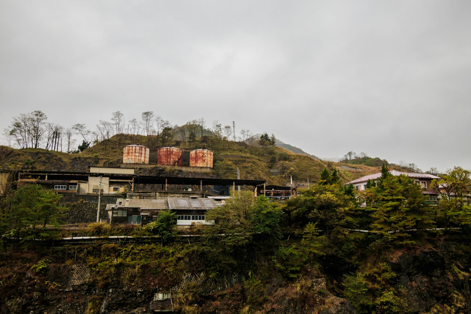 Paesaggio con vecchi edifici e serbatoi rossi su una collina