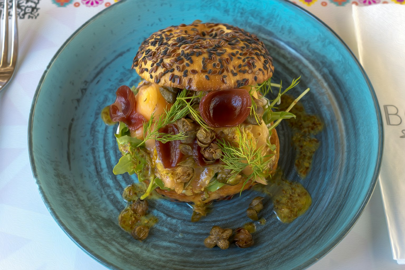 A beautifully plated burger with fresh greens on a vibrant blue dish