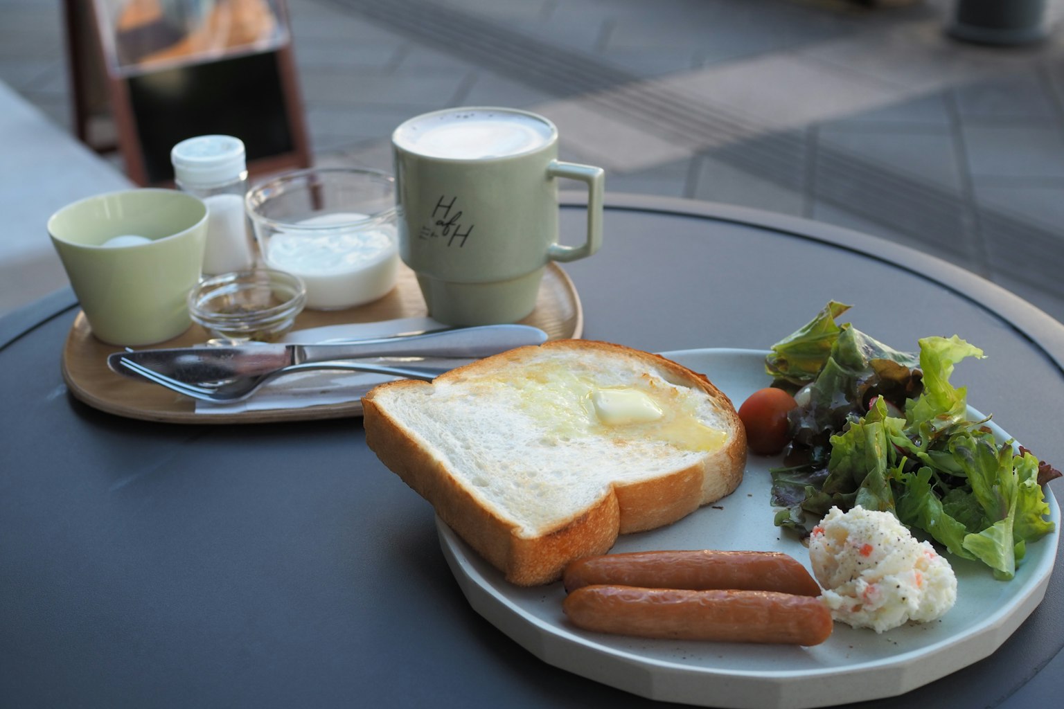 Desayuno con tostadas salchichas ensalada y bebidas en una mesa