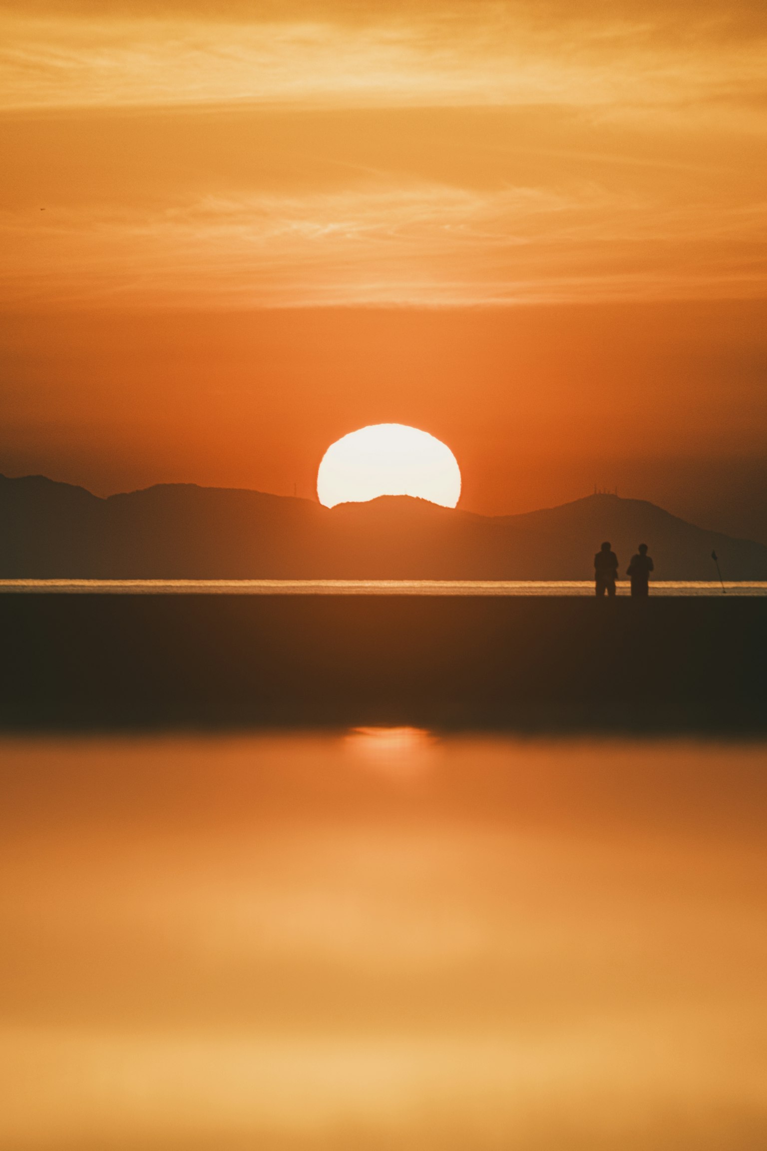 海边日落时两个人的轮廓