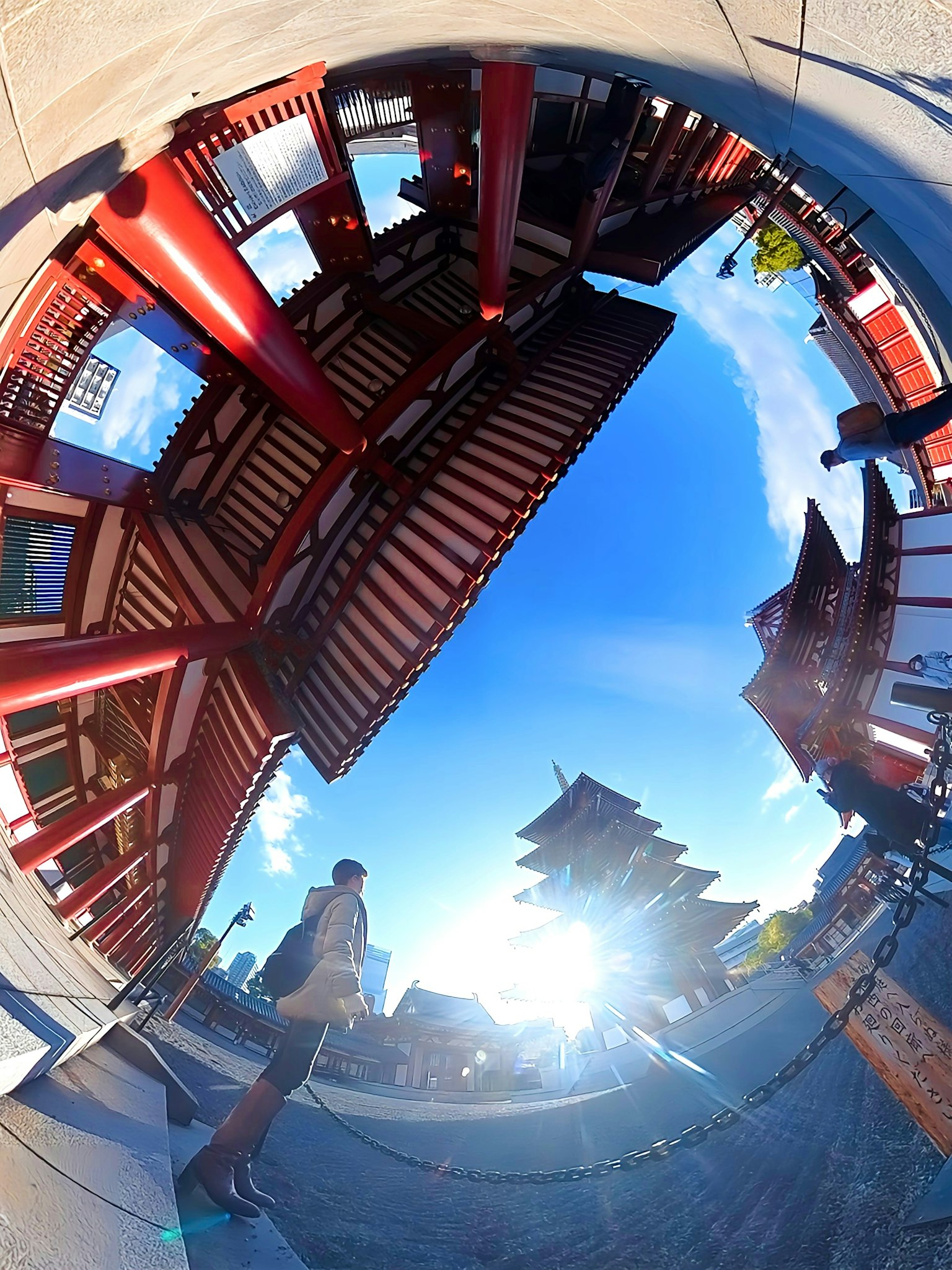Vue fisheye de bâtiments rouges sous un ciel bleu avec une personne debout