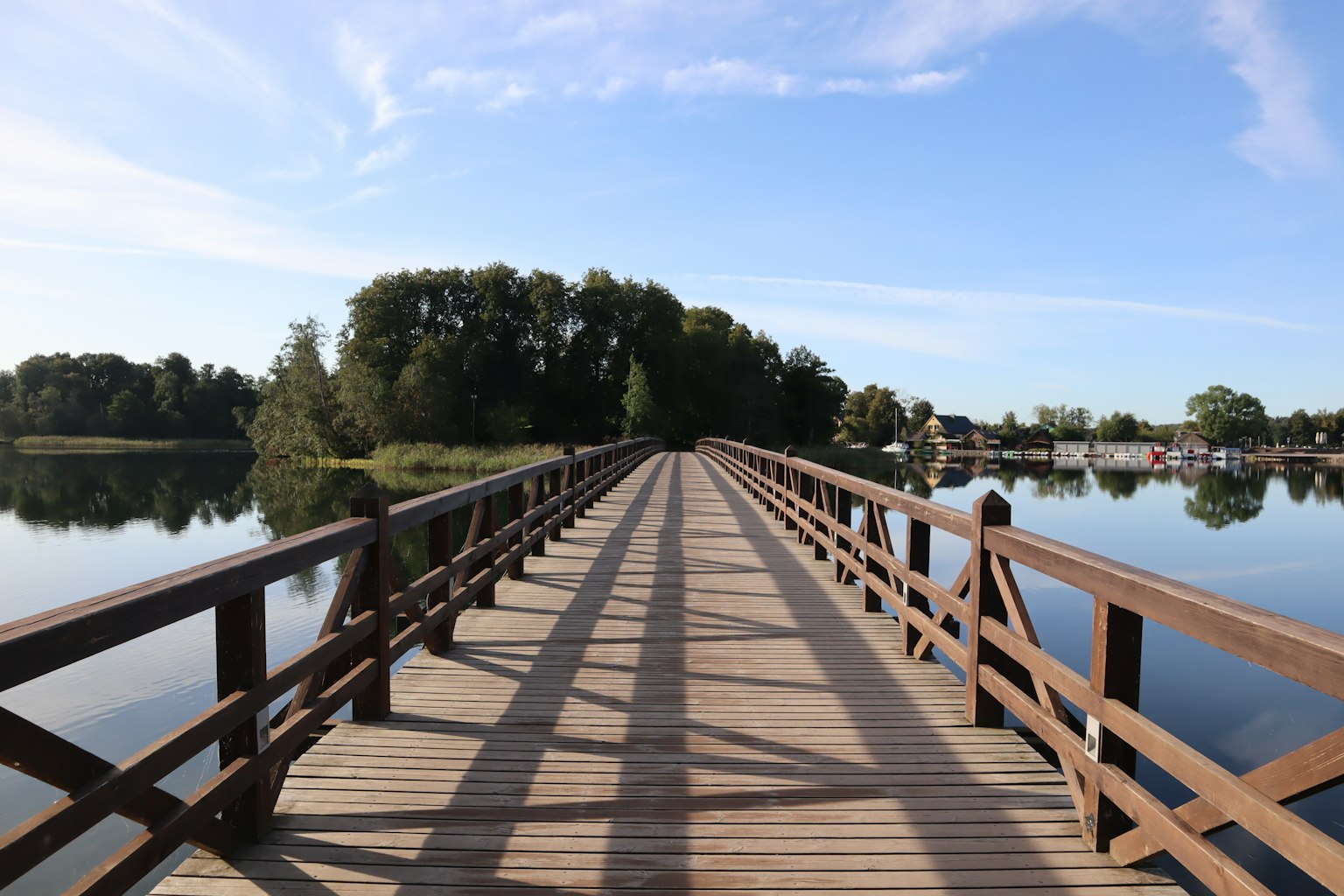 Puente de madera sobre un lago tranquilo rodeado de árboles