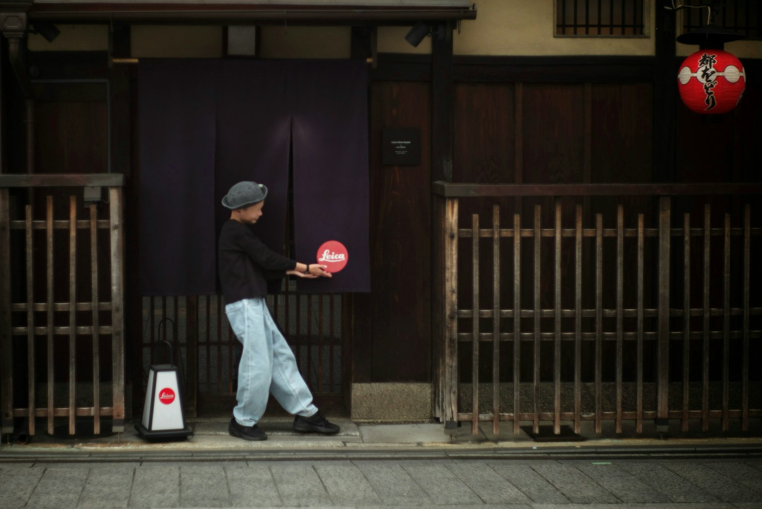 Một người đàn ông đứng trước một tòa nhà truyền thống của Nhật Bản cầm đèn lồng đỏ
