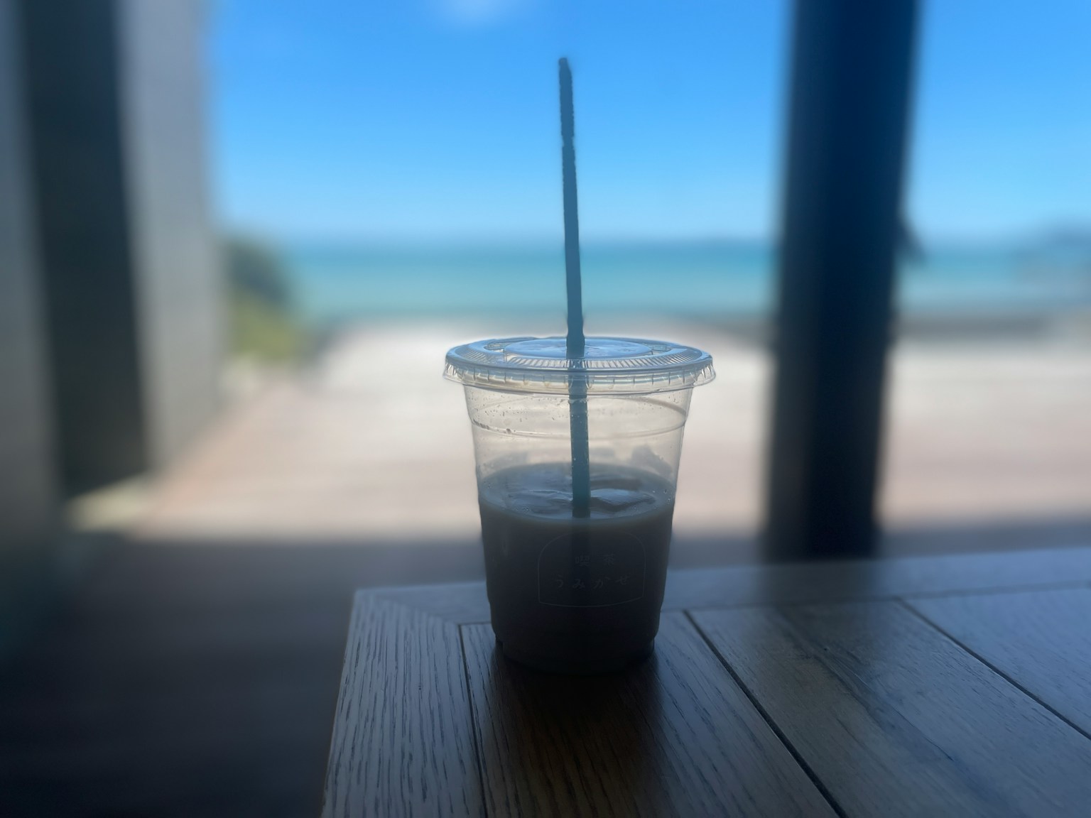 Cangkir transparan dengan minuman di latar belakang laut