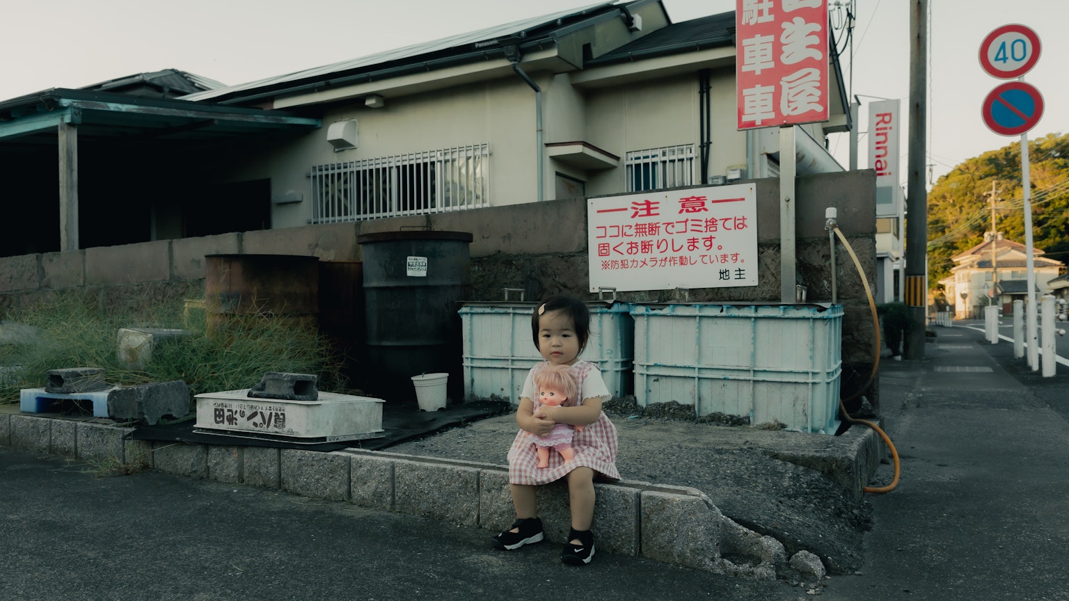 A small child dressed in a yukata sitting on a street corner