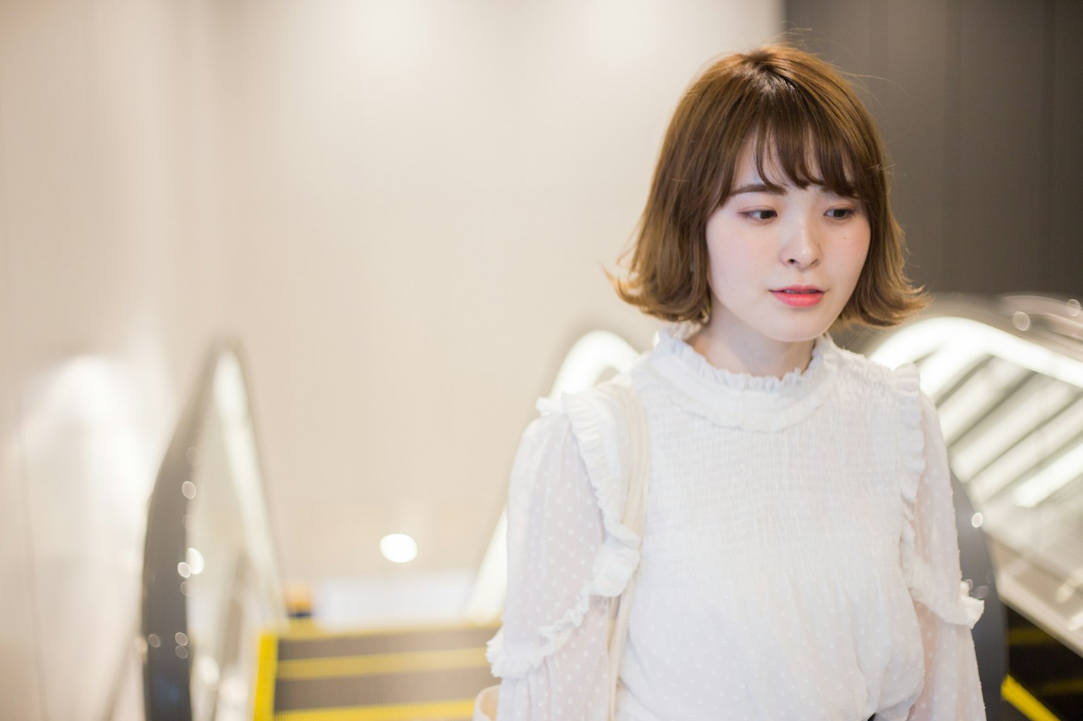 Portrait d'une femme descendant des escaliers portant un chemisier blanc avec une expression calme