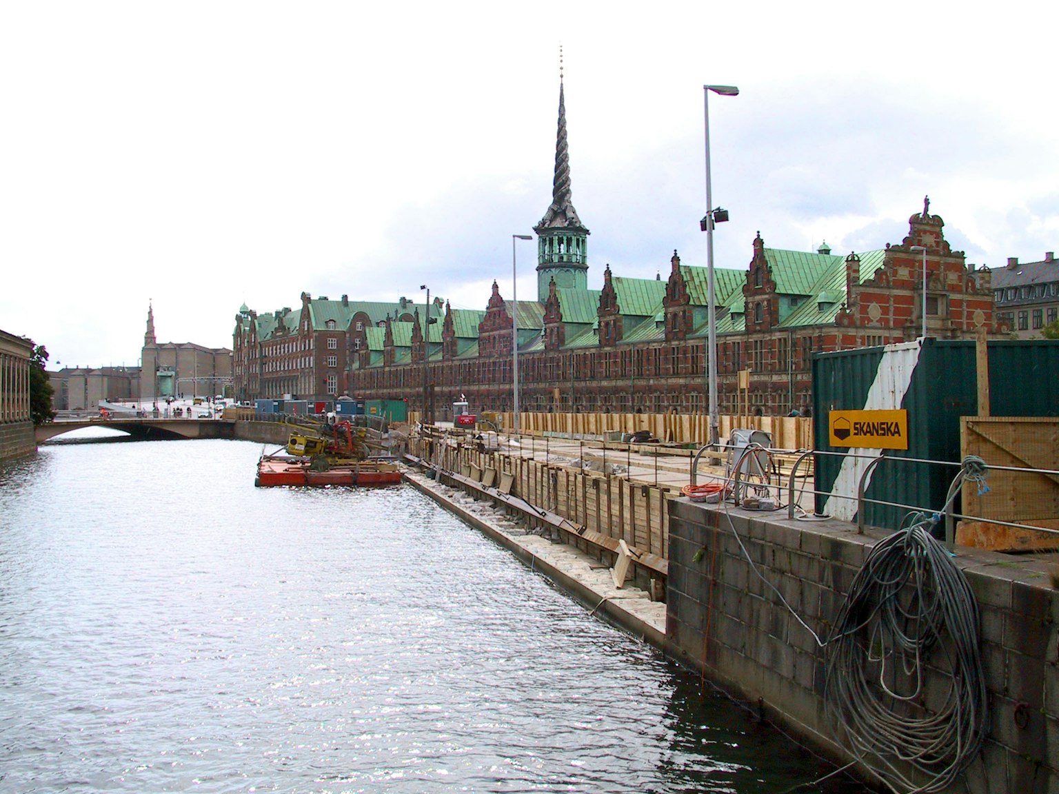Historic buildings along the canal with green roofs and a tall spire