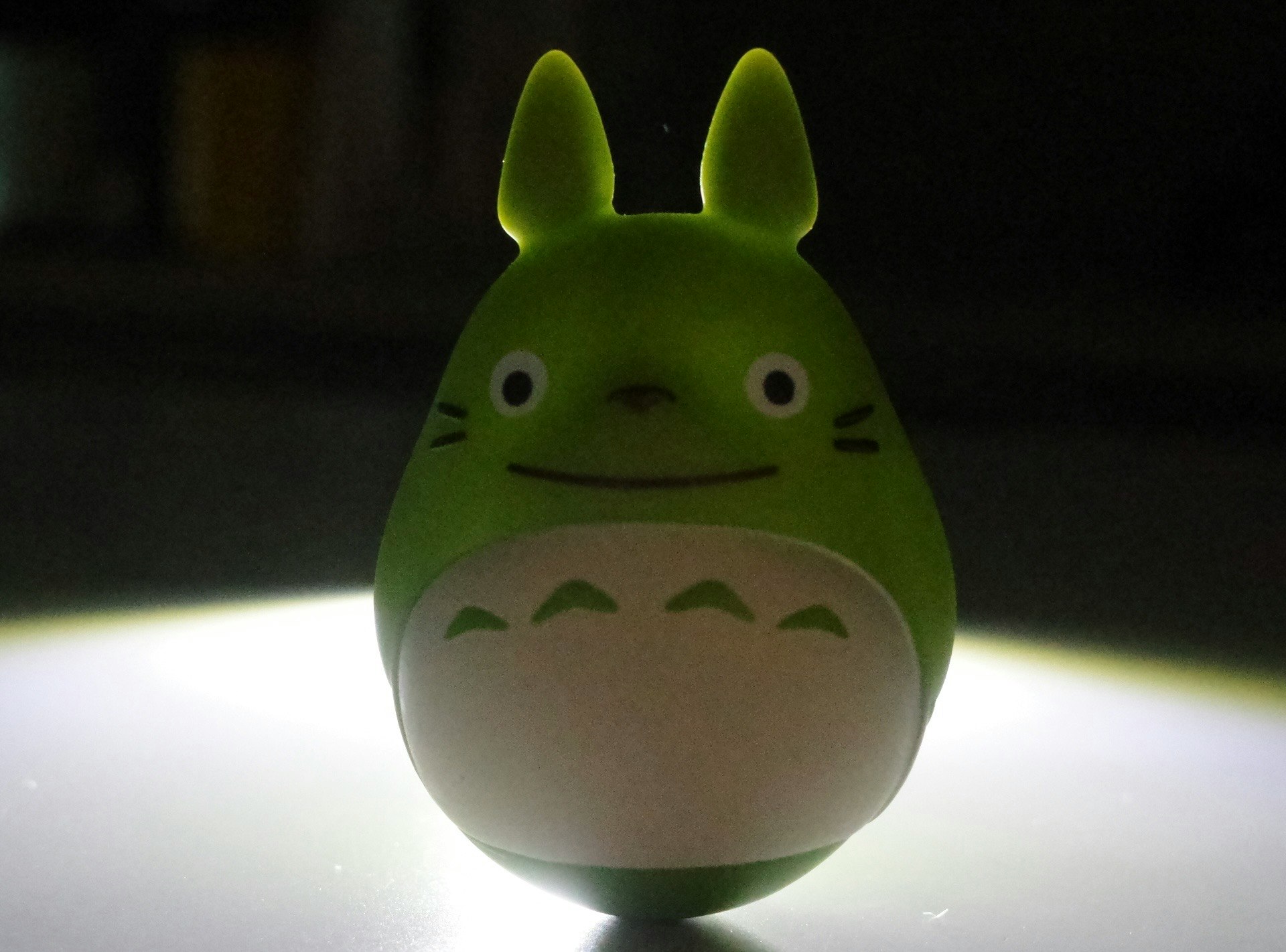 光の中に立つ緑色のトトロのフィギュア