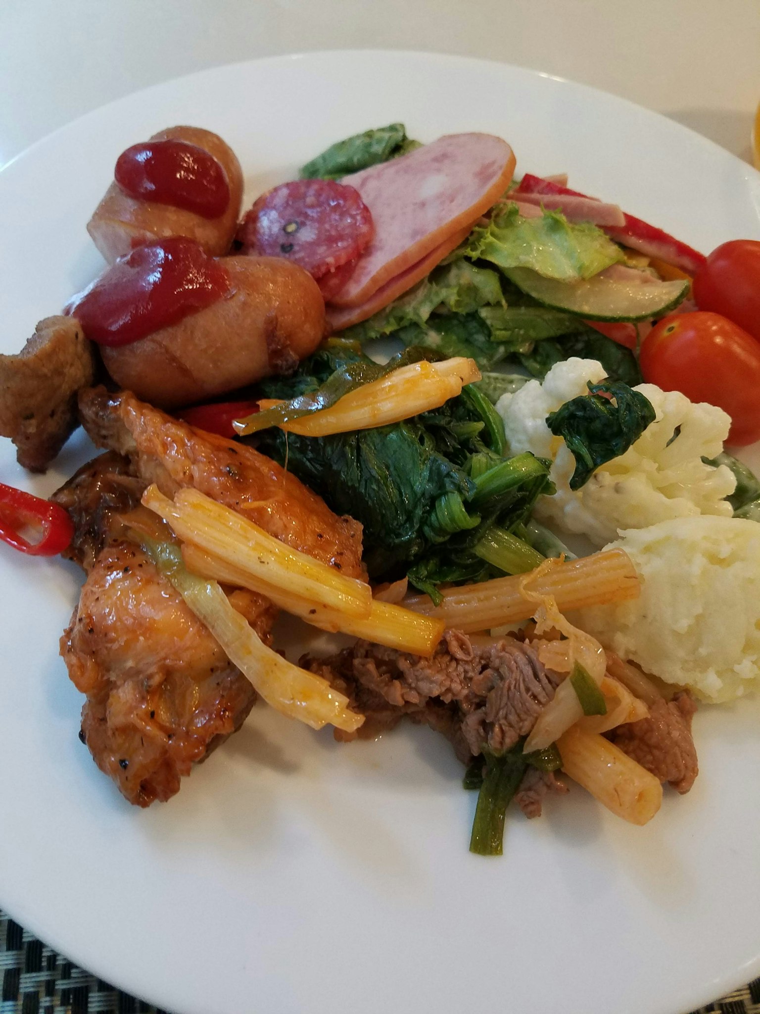 Un plato blanco lleno de verduras coloridas y platos de carne