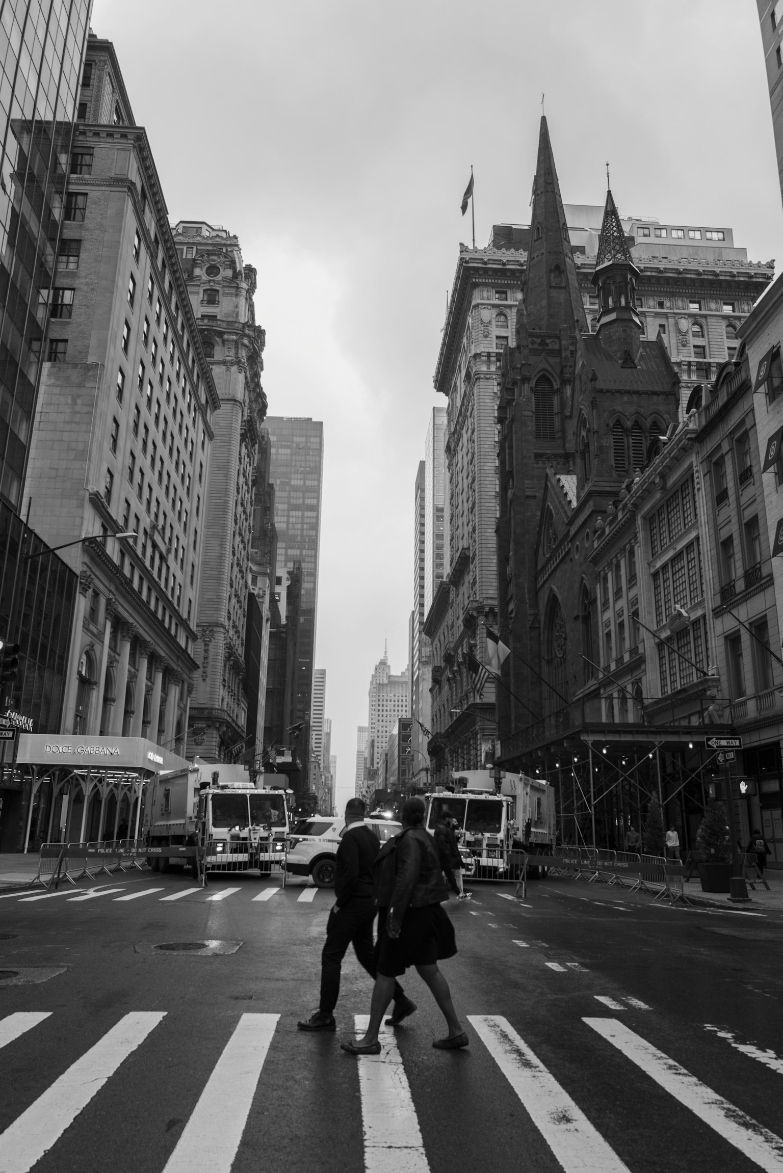 Black and white urban scene featuring two people crossing the street with skyscrapers in the background